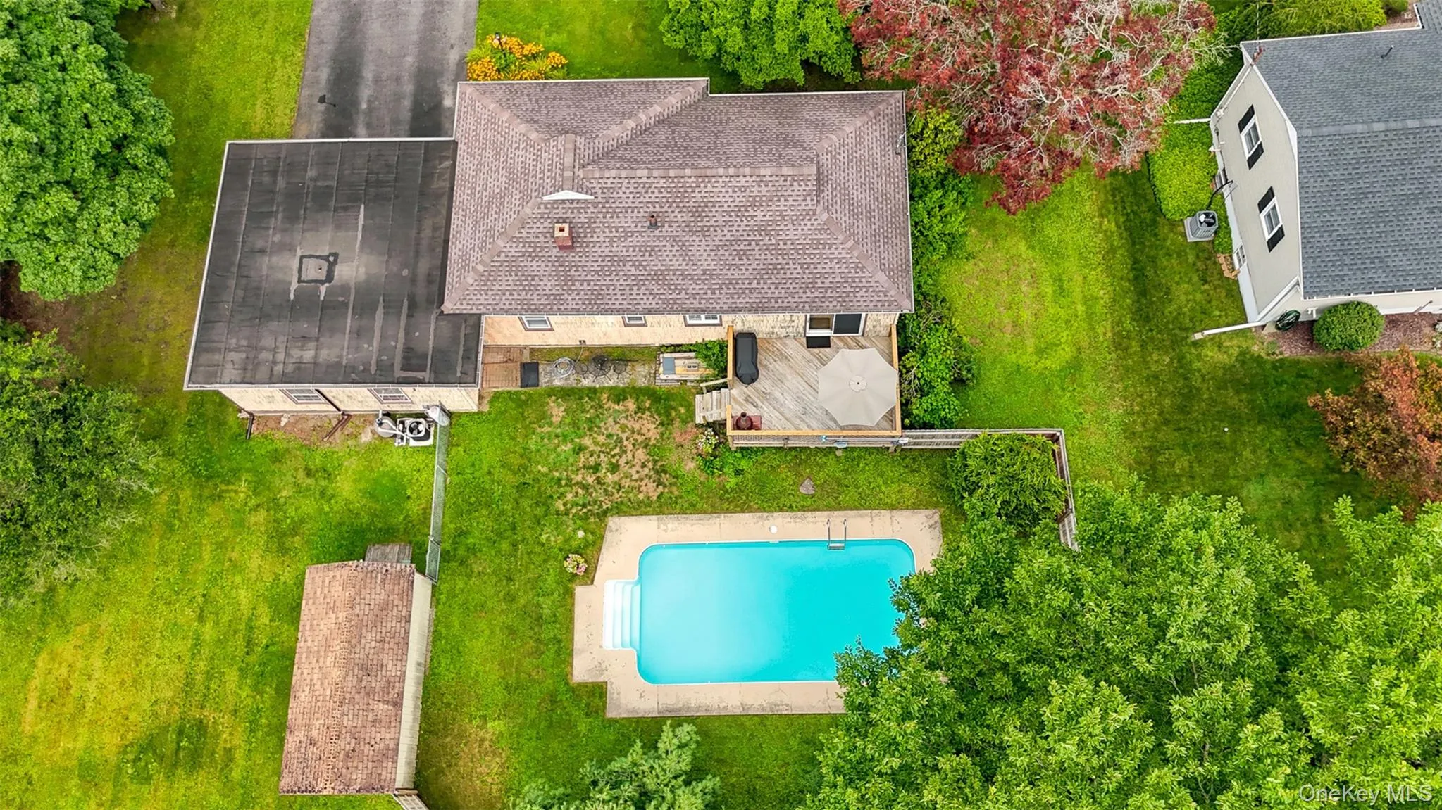 Expansive property featuring a rectangular in-ground swimming pool with steps, a large wood deck, and a detached structure with a flat roof Expansive property featuring a rectangular in-ground swimming pool with steps, a large wood deck, and a detached structure with a flat roof