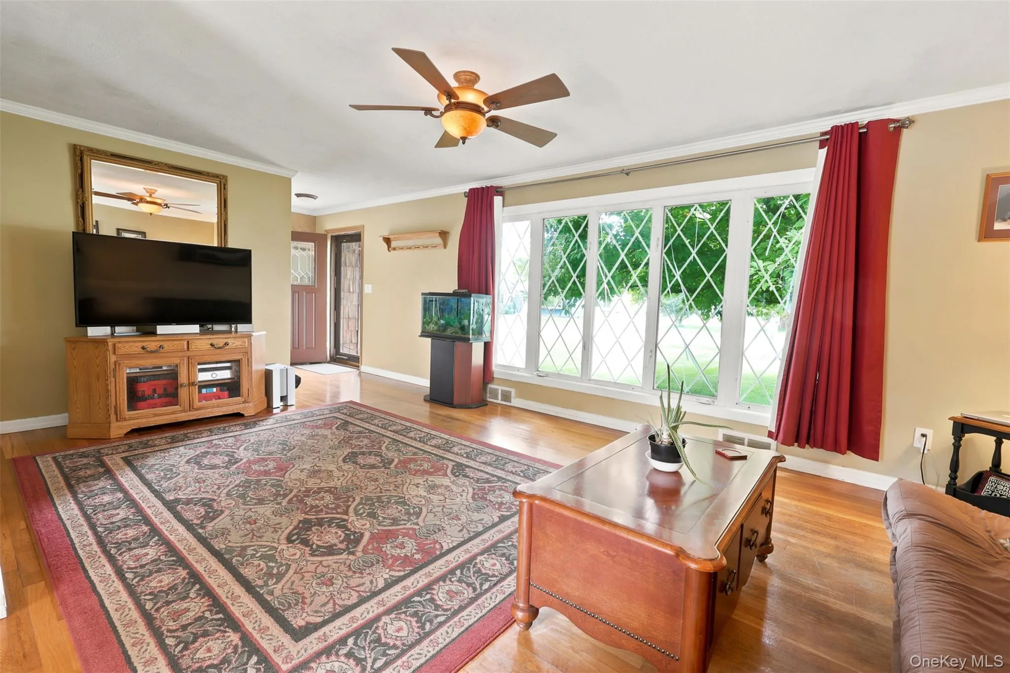 Living area featuring wood-finish flooring, a multi-pane picture window, and a ceiling fan Living area featuring wood-finish flooring, a multi-pane picture window, and a ceiling fan