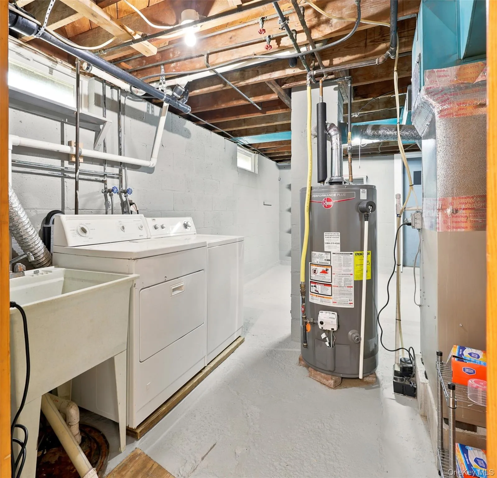 Laundry washer, dryer, and sink in an unfinished basement Laundry washer, dryer, and sink in an unfinished basement