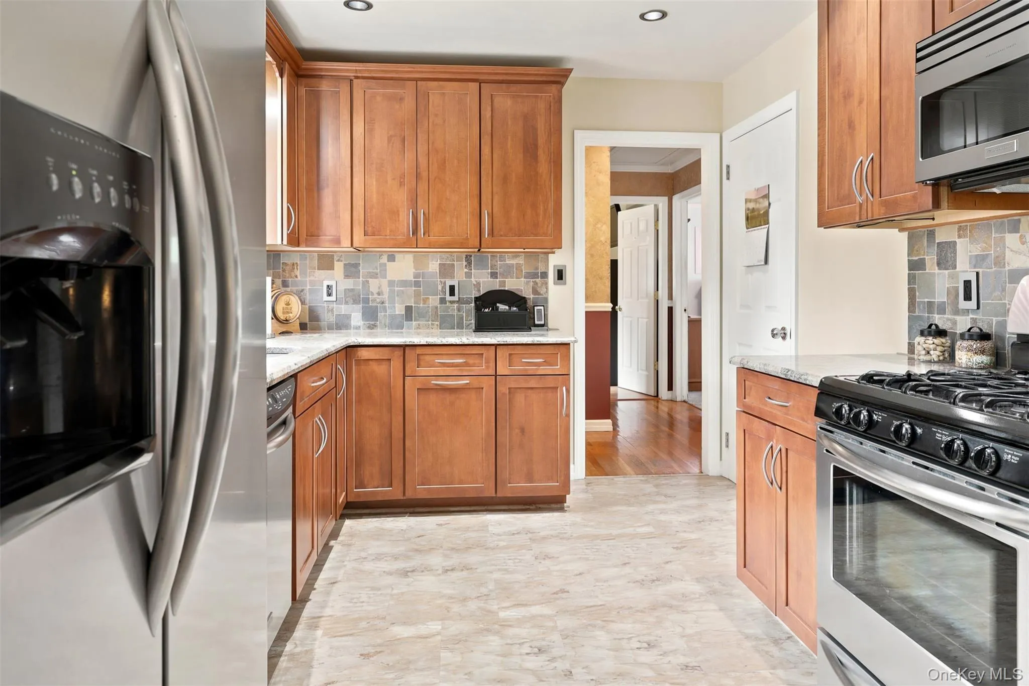 Kitchen featuring granite countertops, wood cabinetry, tile backsplash, stainless steel appliances, and recessed lighting Kitchen featuring granite countertops, wood cabinetry, tile backsplash, stainless steel appliances, and recessed lighting