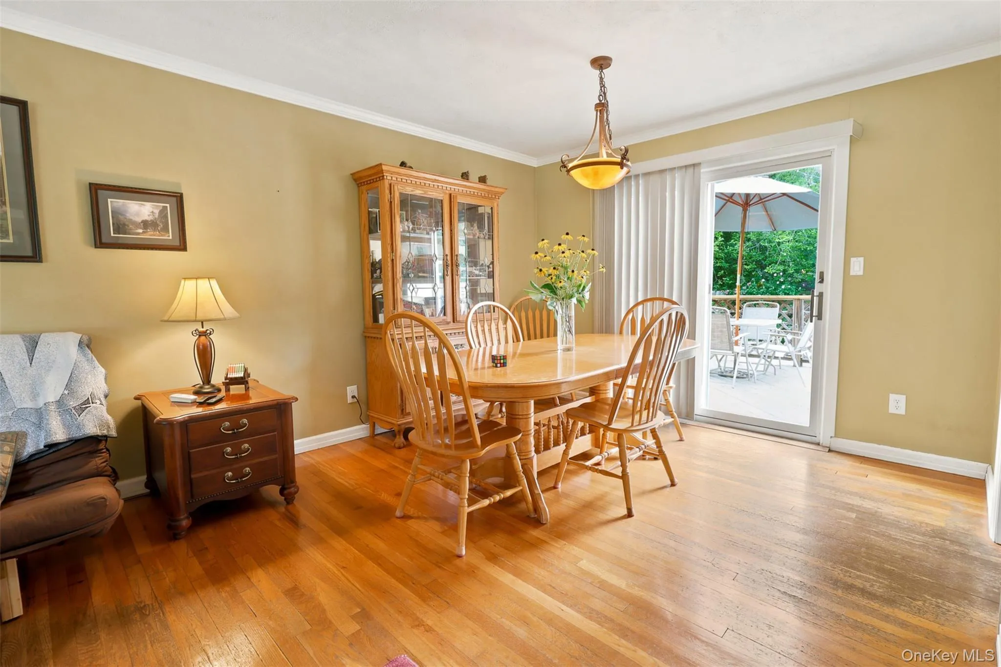Dining area featuring wood-finish flooring, a ceiling-mounted light fixture, and a sliding glass door providing access to an exterior deck Dining area featuring wood-finish flooring, a ceiling-mounted light fixture, and a sliding glass door providing access to an exterior deck
