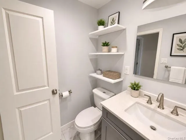 Bathroom featuring a vanity with a white countertop and undermount sink, brushed nickel faucet, and a large mirror Bathroom featuring a vanity with a white countertop and undermount sink, brushed nickel faucet, and a large mirror