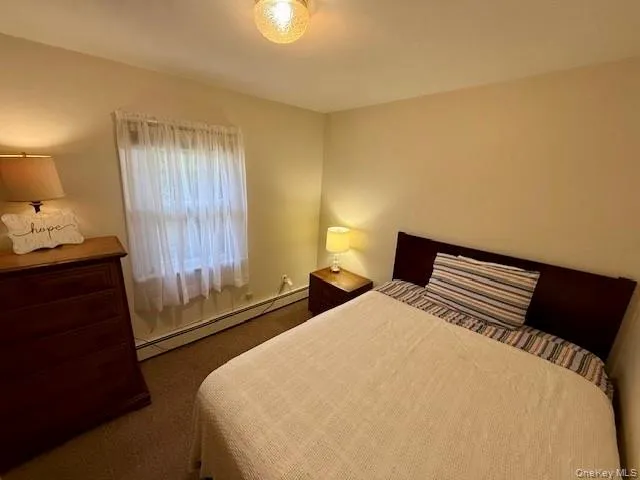 Carpeted bedroom featuring baseboard heating Carpeted bedroom featuring baseboard heating