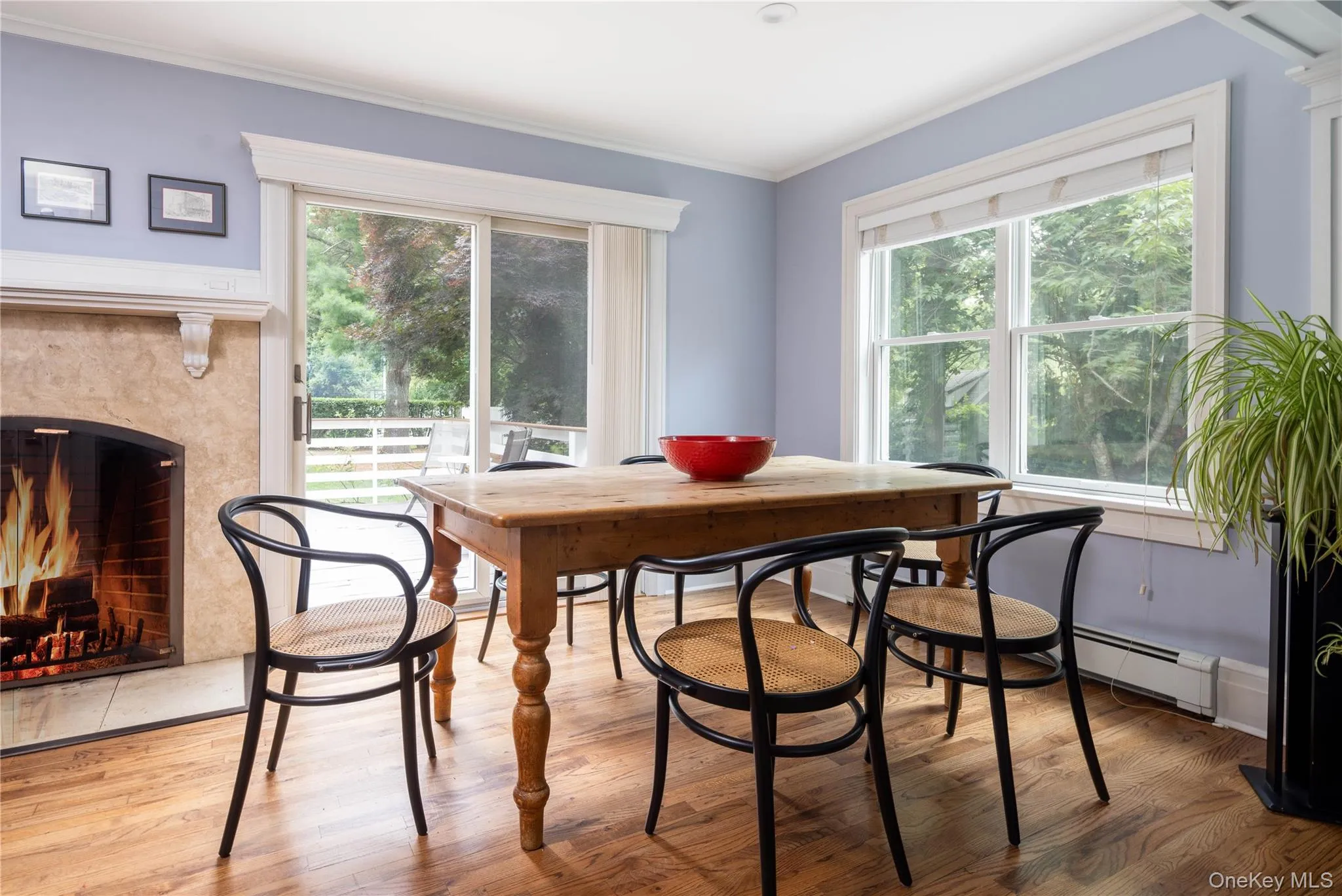Main dining area with hardwood flooring, wood-burning fireplace with stone surround, large windows, and sliding glass door leading to back deck Main dining area with hardwood flooring, wood-burning fireplace with stone surround, large windows, and sliding glass door leading to back deck