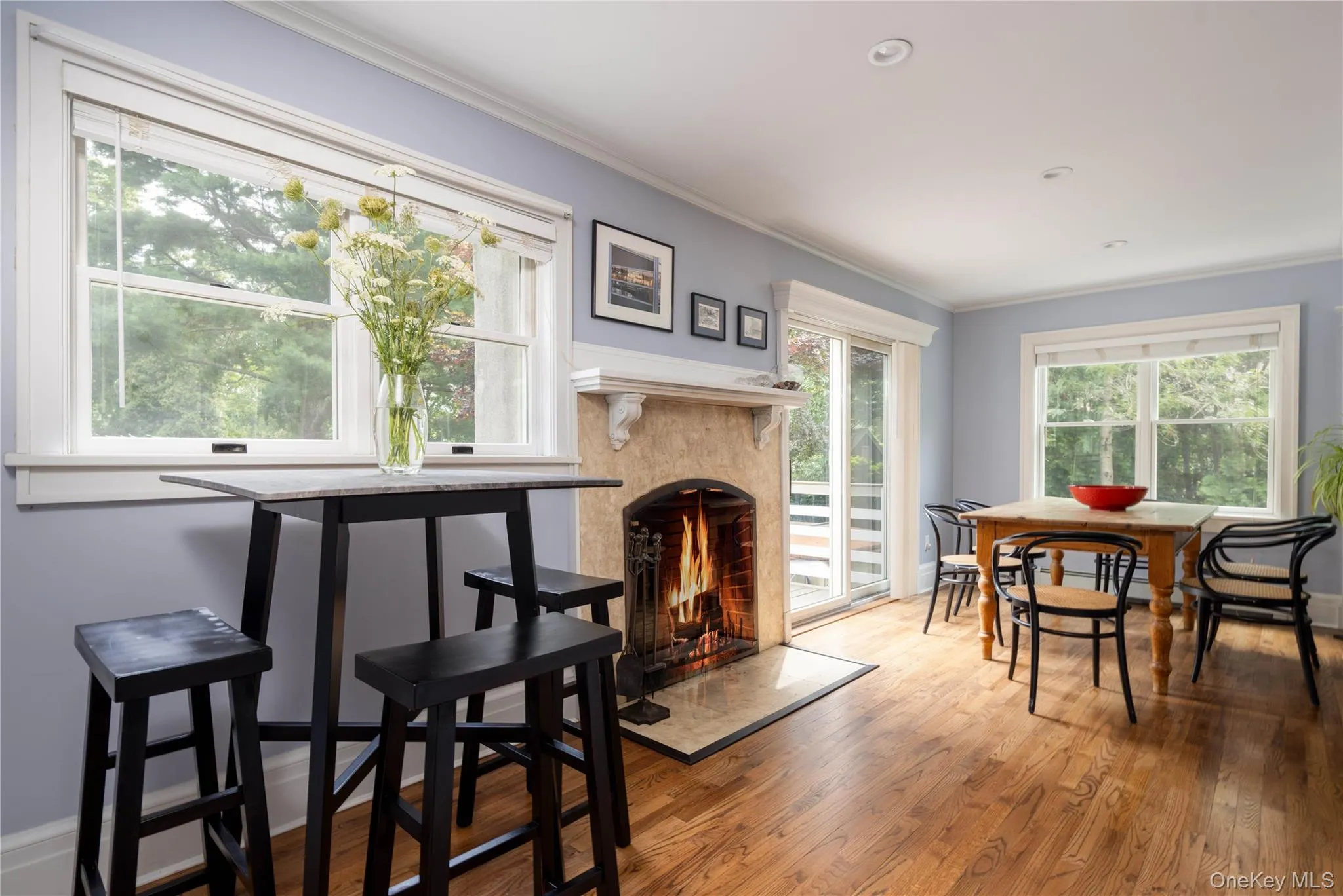 Breakfast bar and main dining area with hardwood flooring, recessed lighting, double-hung windows, stone wood-burning fireplace, and sliding glass doors leading to back deck Breakfast bar and main dining area with hardwood flooring, recessed lighting, double-hung windows, stone wood-burning fireplace, and sliding glass doors leading to back deck