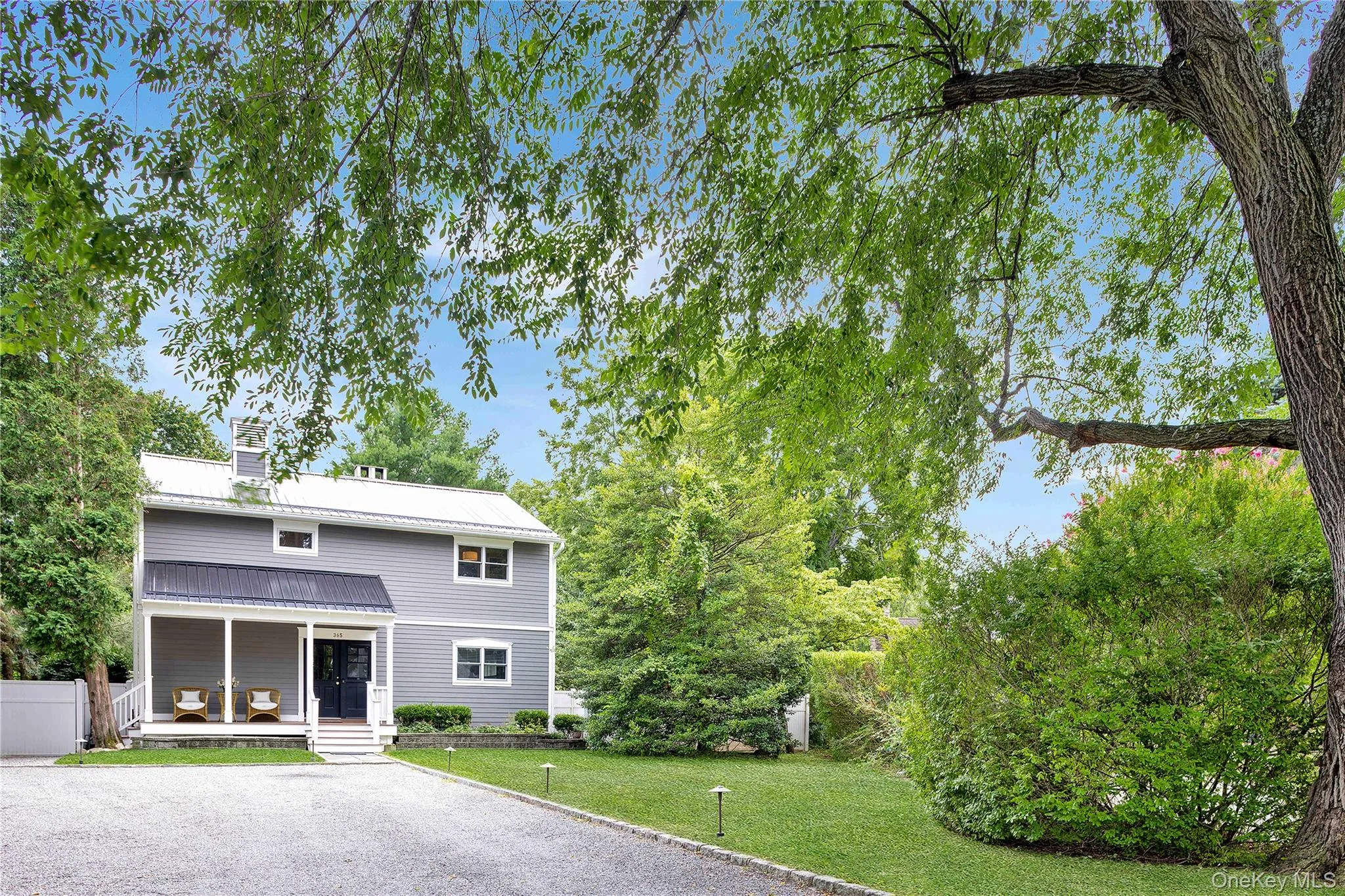 Front of home with cobblestone-edged driveway, covered front porch and metal roof Front of home with cobblestone-edged driveway, covered front porch and metal roof