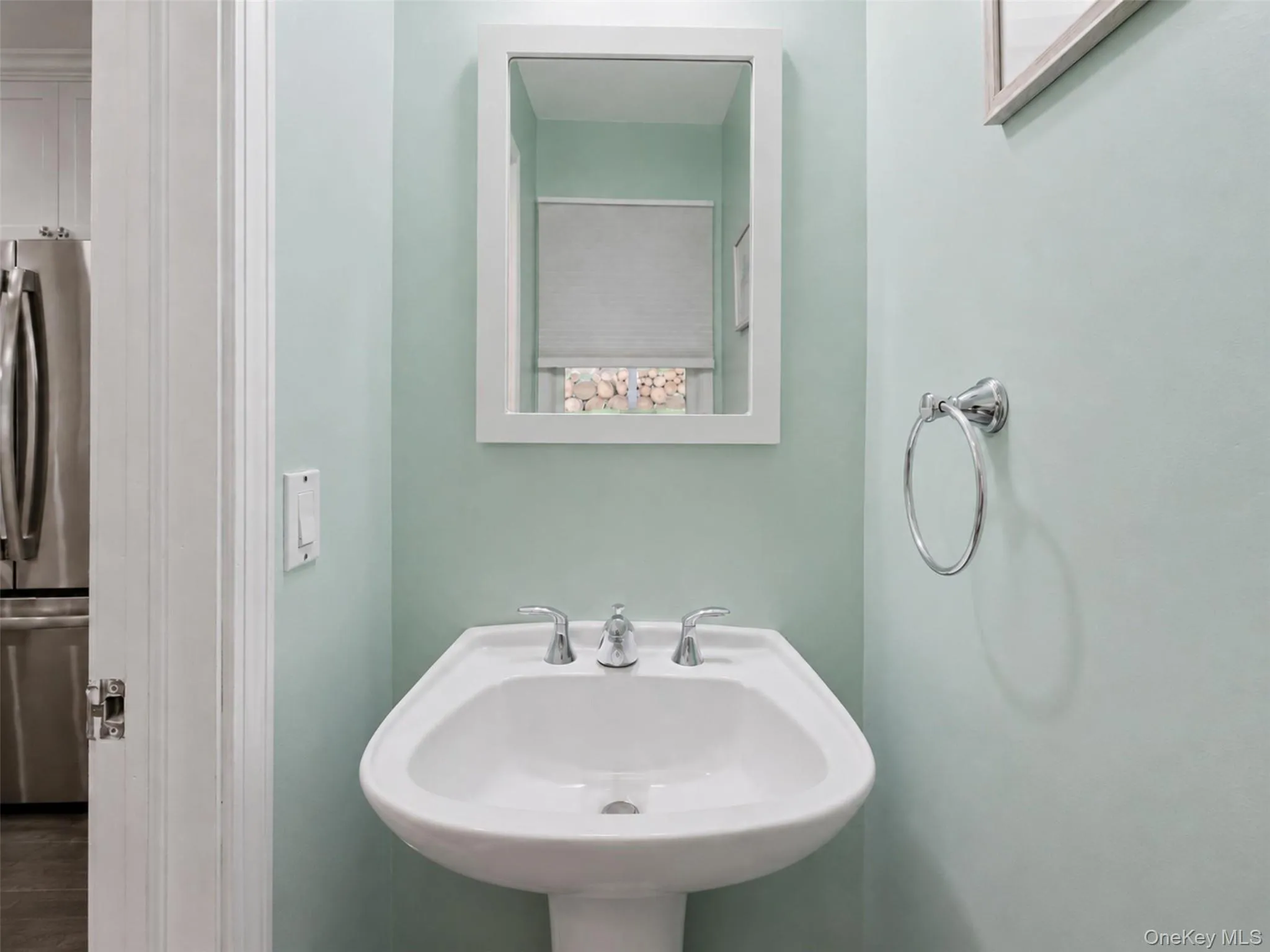 Pedestal sink featuring chrome fixtures and a framed mirror Pedestal sink featuring chrome fixtures and a framed mirror