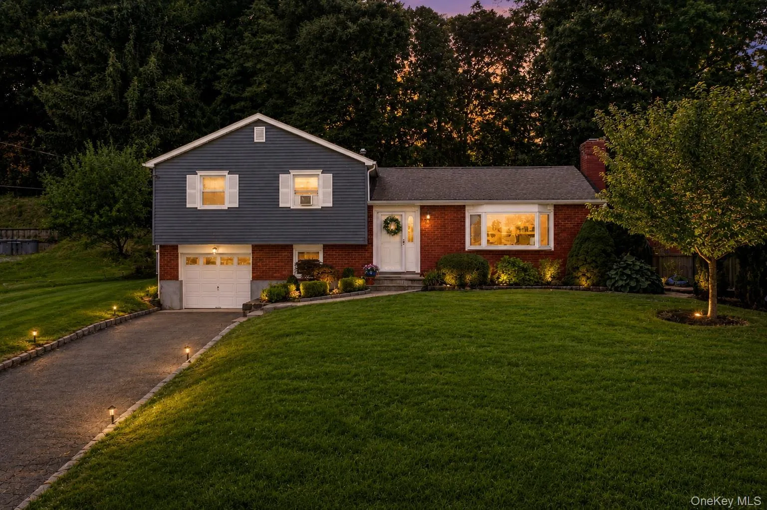 Split-level residence featuring a brick facade with bay window and complementary siding Split-level residence featuring a brick facade with bay window and complementary siding