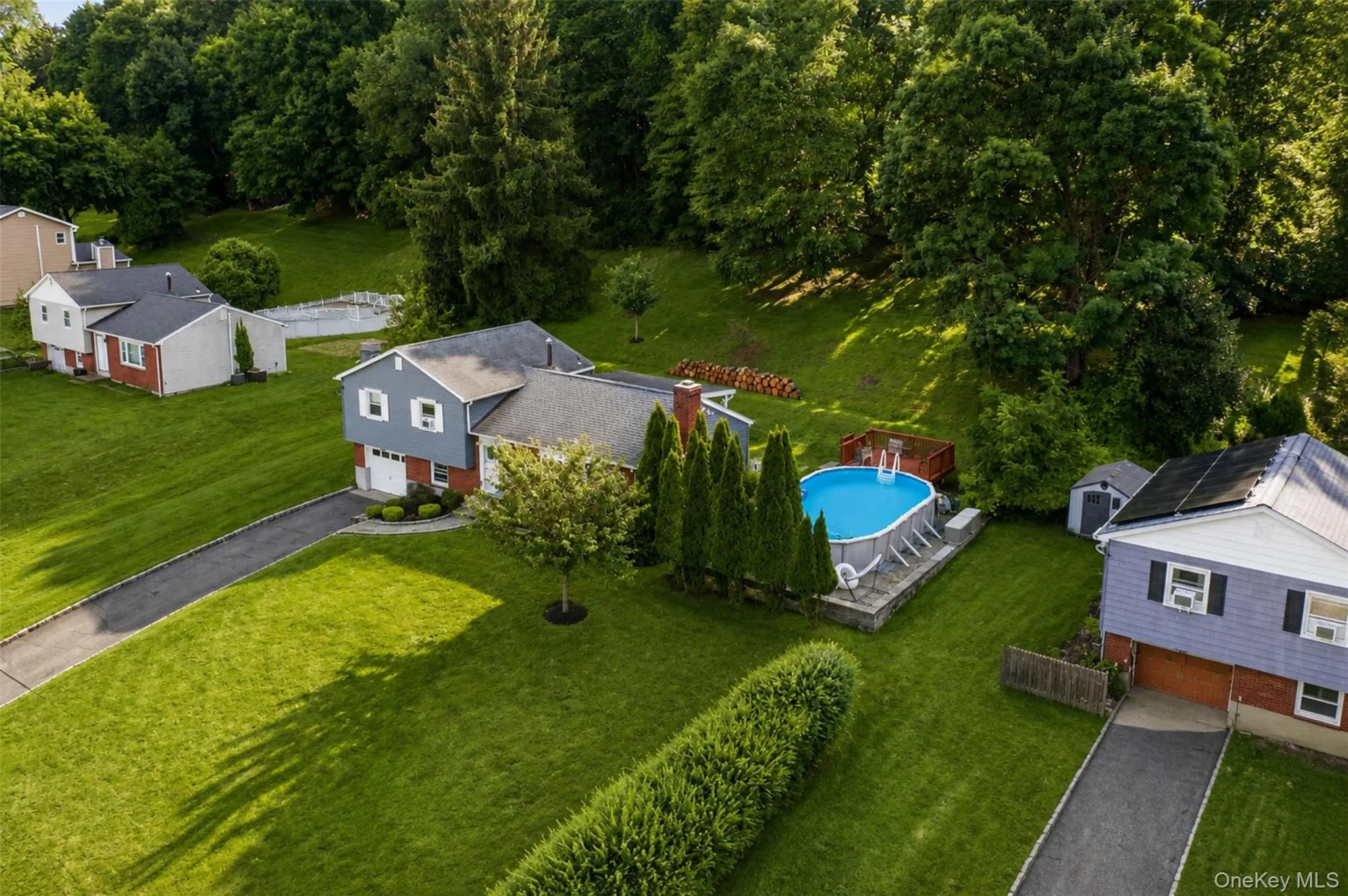 Expansive backyard featuring an above-ground swimming pool, surrounding deck, and mature privacy plantings Expansive backyard featuring an above-ground swimming pool, surrounding deck, and mature privacy plantings