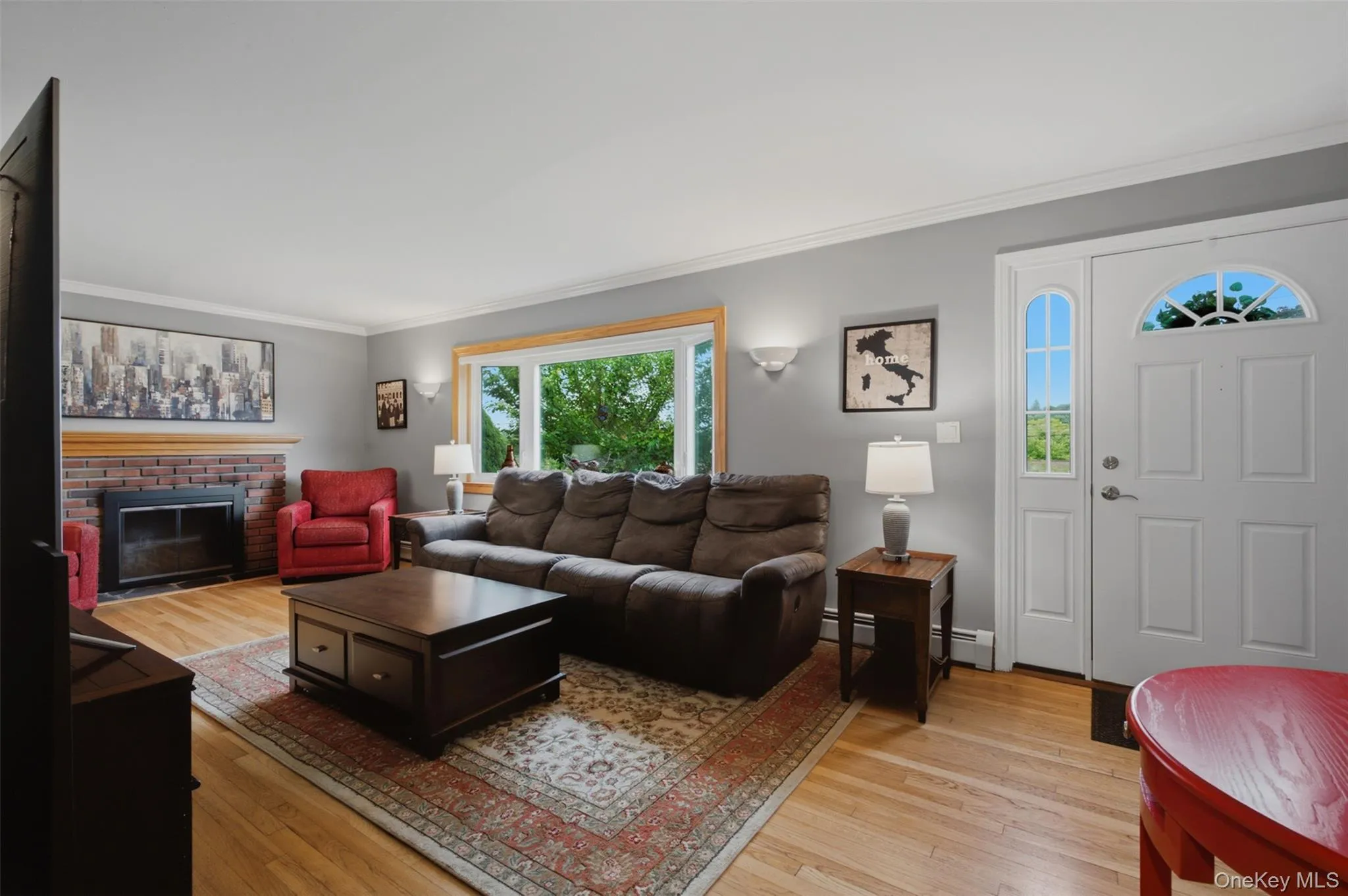 Hardwood flooring extends throughout this room, featuring a brick fireplace Hardwood flooring extends throughout this room, featuring a brick fireplace