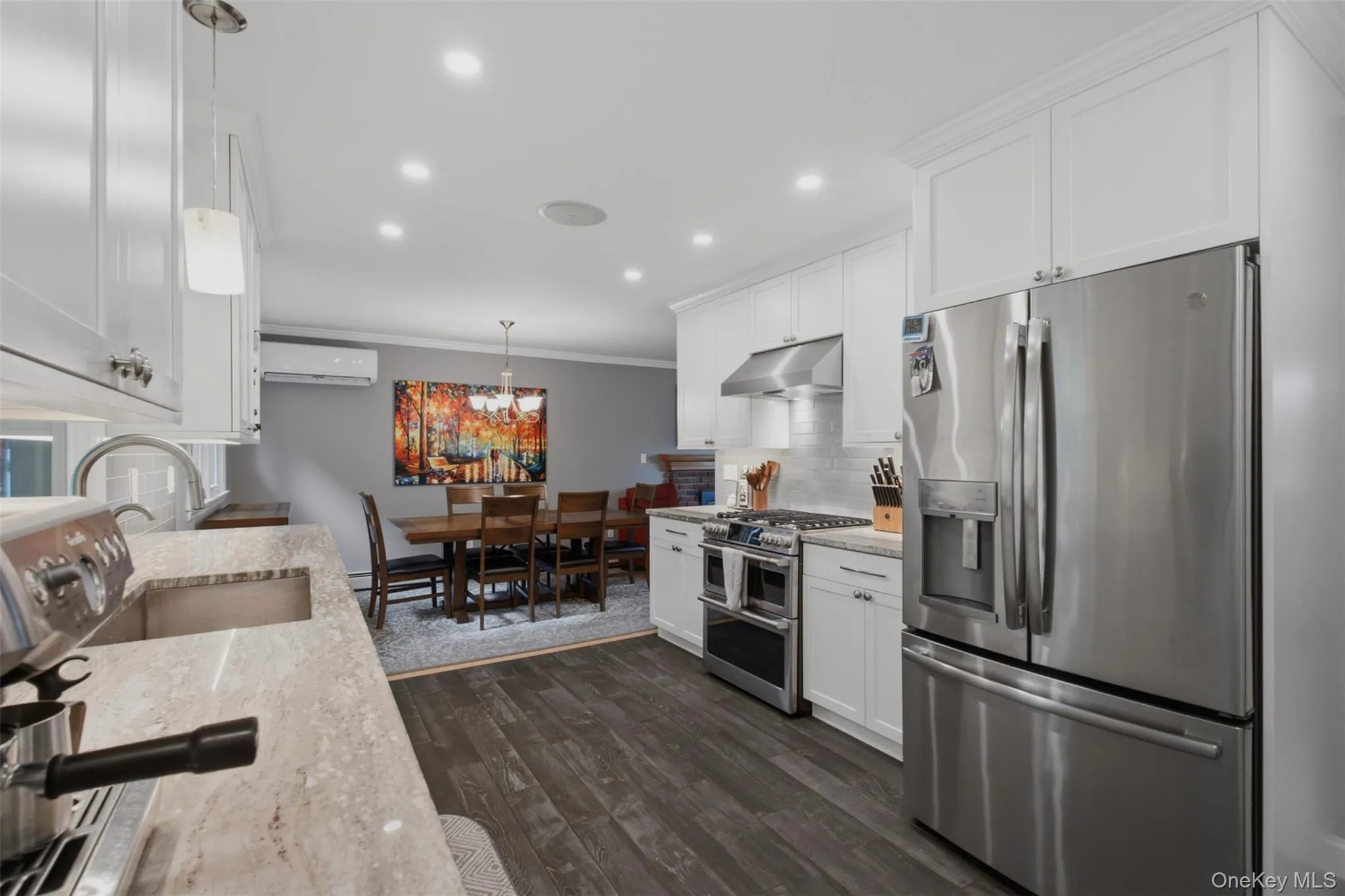 Modern kitchen featuring stainless steel appliances, white cabinetry, undermount sink, recessed lighting, and wood-finish flooring Modern kitchen featuring stainless steel appliances, white cabinetry, undermount sink, recessed lighting, and wood-finish flooring