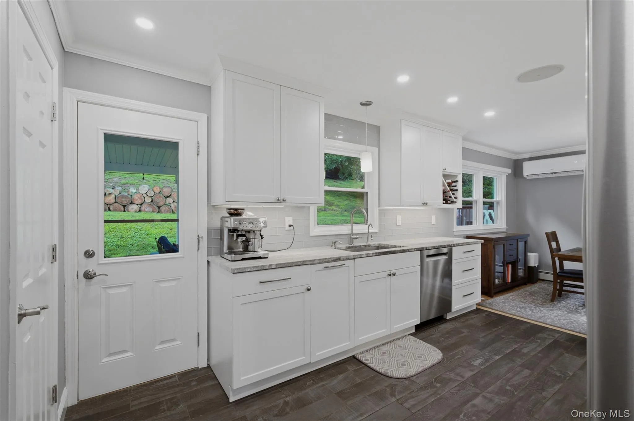 Modern kitchen featuring white shaker cabinetry, stainless steel dishwasher, and stone-finish countertops Modern kitchen featuring white shaker cabinetry, stainless steel dishwasher, and stone-finish countertops