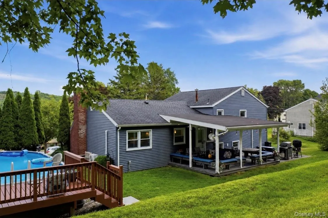 Expansive backyard featuring a covered patio, tiered wooden deck, and an above-ground swimming pool Expansive backyard featuring a covered patio, tiered wooden deck, and an above-ground swimming pool