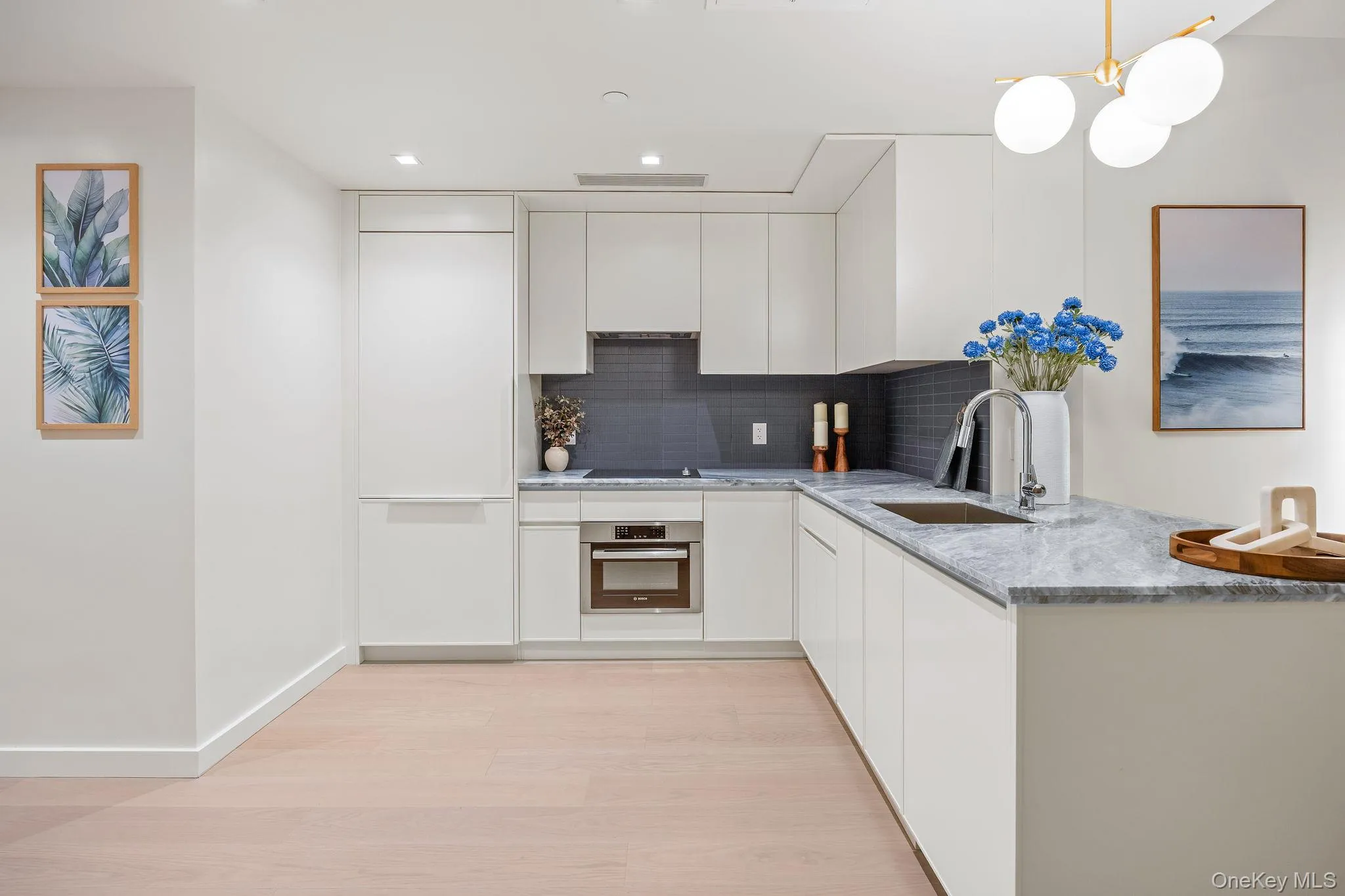 Kitchen with white cabinetry, light stone countertops, decorative backsplash, light wood-type flooring, and oven Kitchen with white cabinetry, light stone countertops, decorative backsplash, light wood-type flooring, and oven