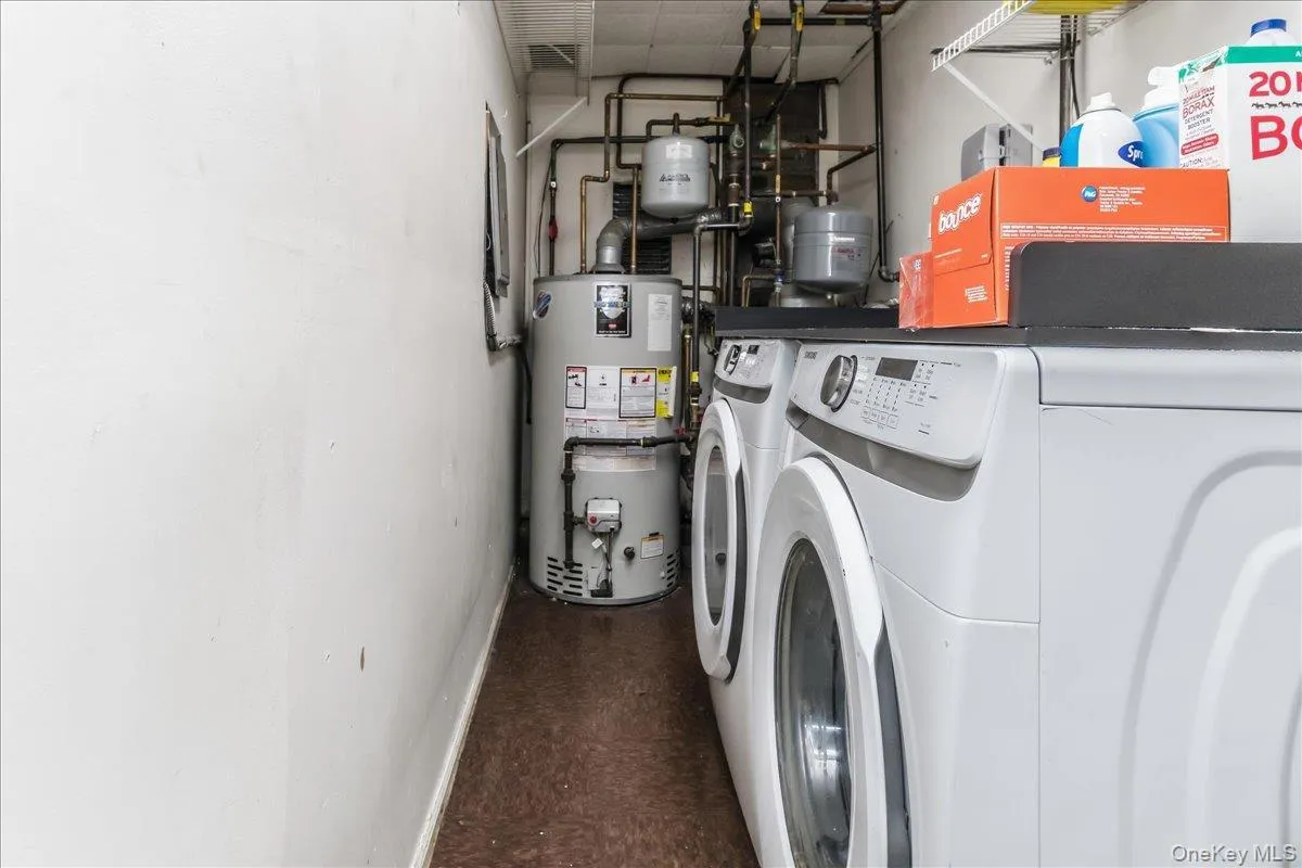 Utility area featuring a side-by-side washer and dryer, water heater, and exposed plumbing Utility area featuring a side-by-side washer and dryer, water heater, and exposed plumbing