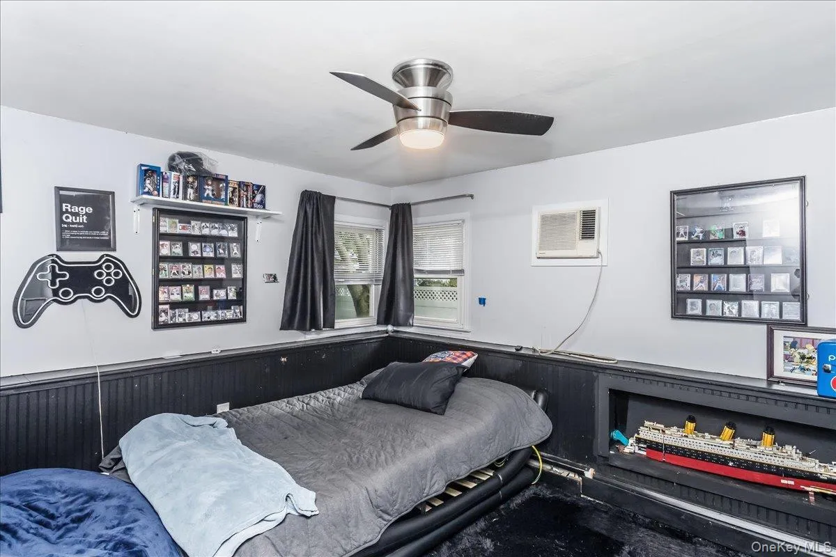 Room featuring a ceiling fan with integrated lighting, white walls, and dark wainscoting Room featuring a ceiling fan with integrated lighting, white walls, and dark wainscoting