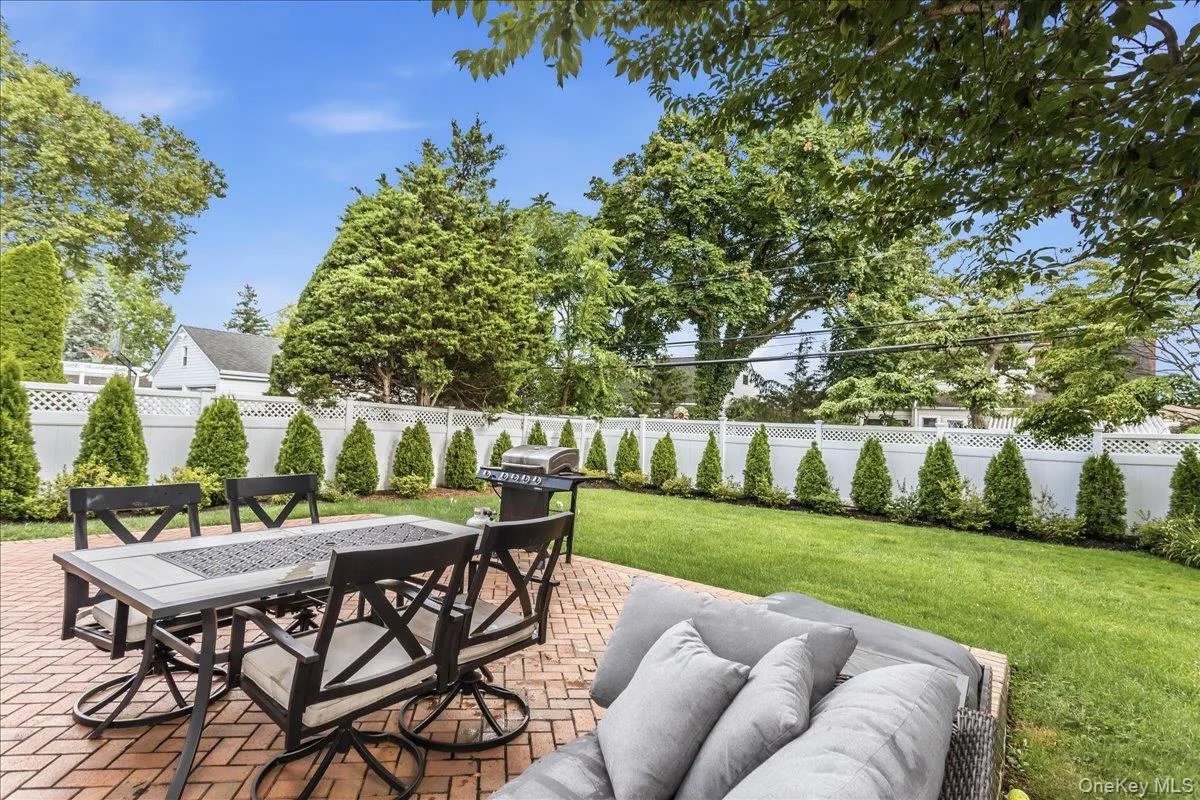 Expansive backyard featuring a brick paver patio, lush green lawn, and mature perimeter trees Expansive backyard featuring a brick paver patio, lush green lawn, and mature perimeter trees