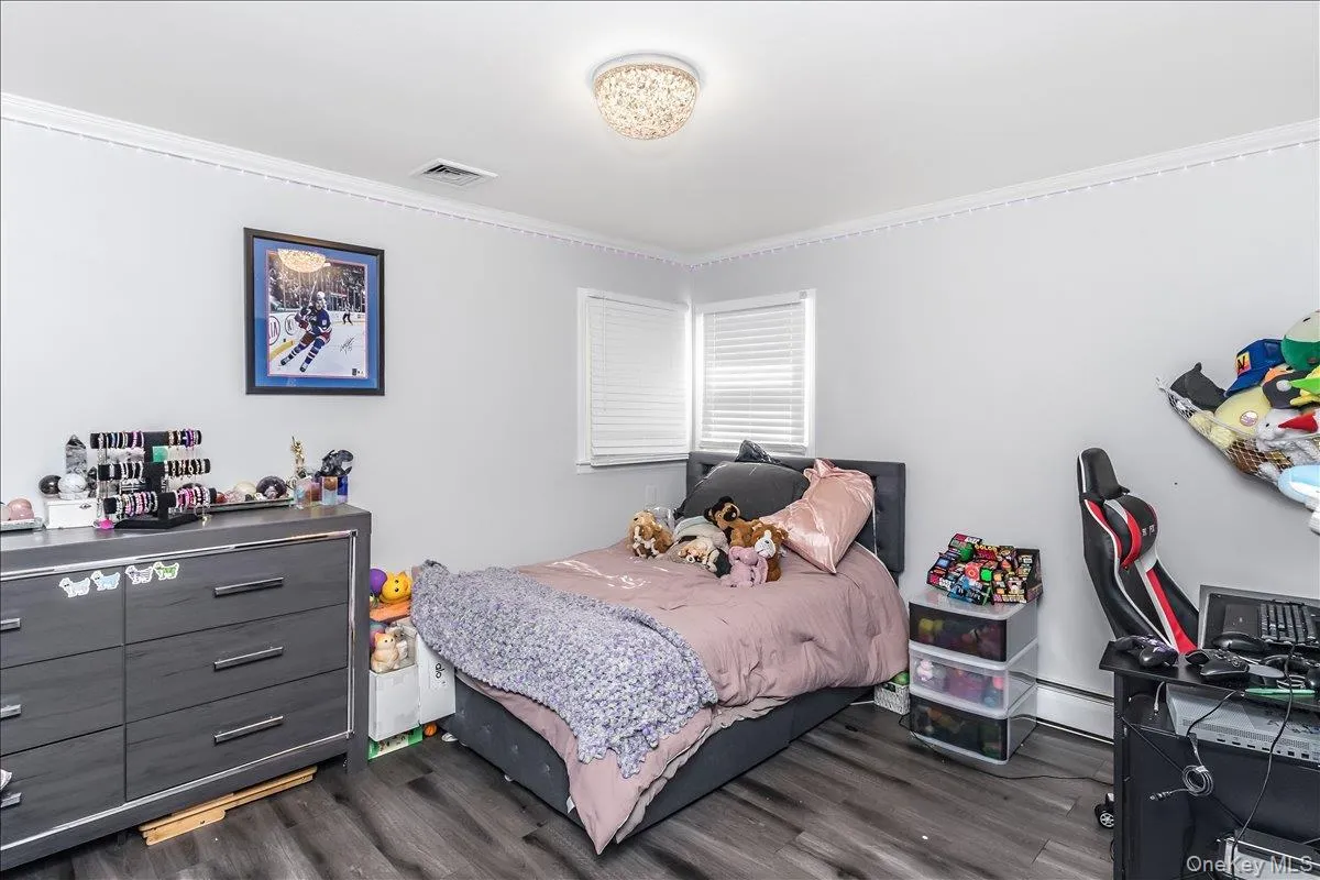 Room featuring wood-finish flooring, white walls, and crown molding Room featuring wood-finish flooring, white walls, and crown molding