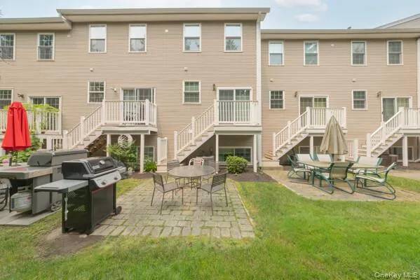 Rear exterior featuring tan siding, multiple second-story balconies with white railings, and sliding glass doors Rear exterior featuring tan siding, multiple second-story balconies with white railings, and sliding glass doors