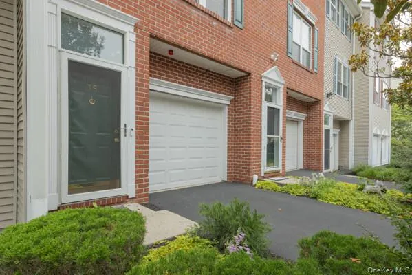Brick facade townhome with an attached garage and a concrete walkway leading to the front entry Brick facade townhome with an attached garage and a concrete walkway leading to the front entry