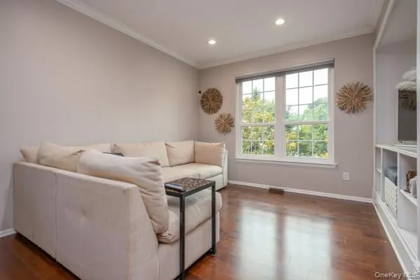 Living area featuring wood-finish flooring, recessed lighting, and crown molding Living area featuring wood-finish flooring, recessed lighting, and crown molding