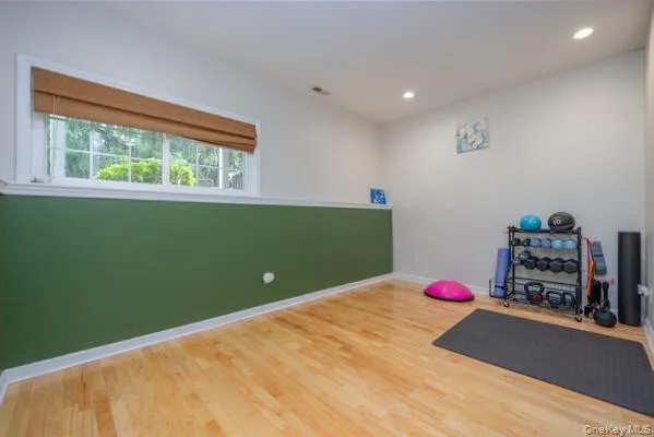 Room with wood-finish flooring, recessed lighting, and a white and green two-tone wall treatment Room with wood-finish flooring, recessed lighting, and a white and green two-tone wall treatment