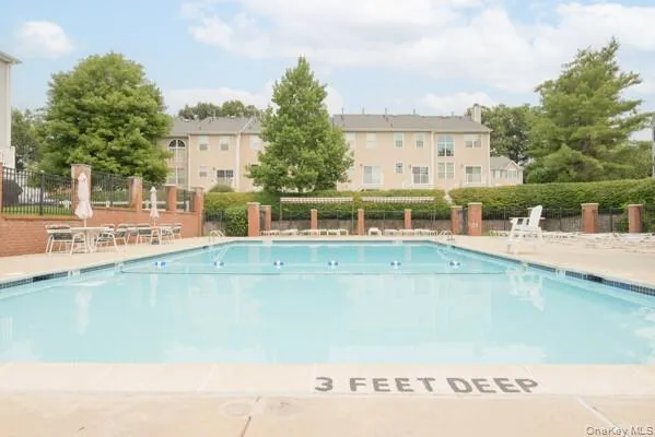 Outdoor swimming pool featuring a concrete deck and blue tile trim Outdoor swimming pool featuring a concrete deck and blue tile trim