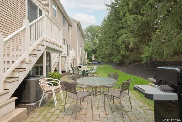 Brick paver patio with ample space for outdoor dining, bordered by a manicured lawn and mature evergreen trees Brick paver patio with ample space for outdoor dining, bordered by a manicured lawn and mature evergreen trees