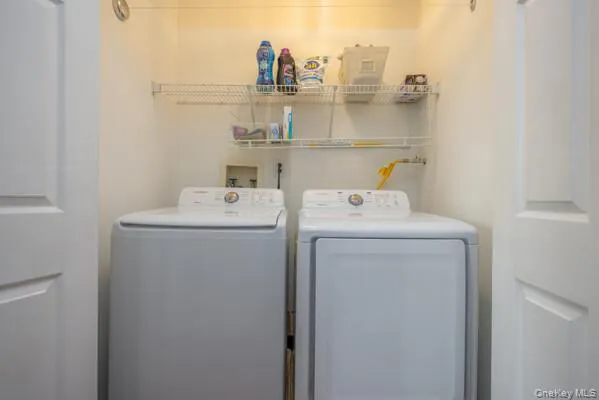 Dedicated laundry area featuring side-by-side washer and dryer with stacked storage shelving above Dedicated laundry area featuring side-by-side washer and dryer with stacked storage shelving above