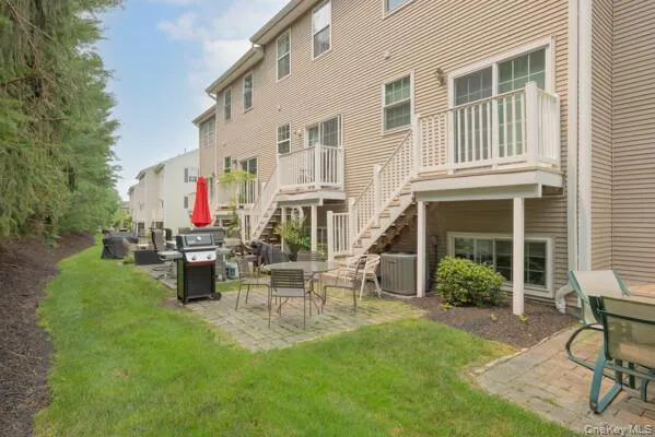 Rear exterior featuring siding, dual-level decks with white railings, and a ground-level patio with pavers Rear exterior featuring siding, dual-level decks with white railings, and a ground-level patio with pavers