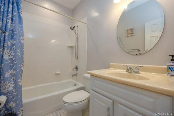 Bathroom featuring a white tub with subway tile surround, white vanity with integrated sink, chrome fixtures, and a circular mirror Bathroom featuring a white tub with subway tile surround, white vanity with integrated sink, chrome fixtures, and a circular mirror