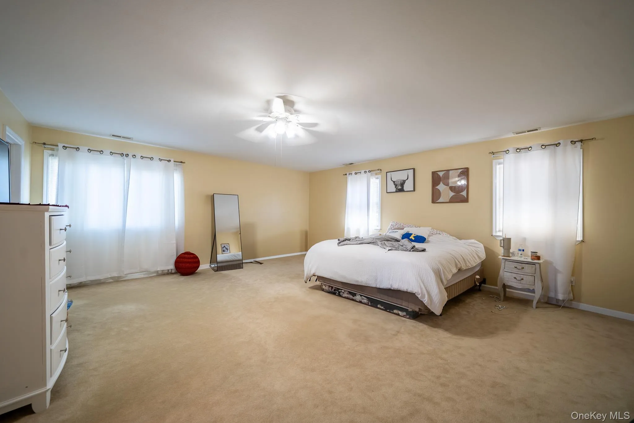 Bedroom featuring ceiling fan, light carpet, visible vents, and baseboards Bedroom featuring ceiling fan, light carpet, visible vents, and baseboards