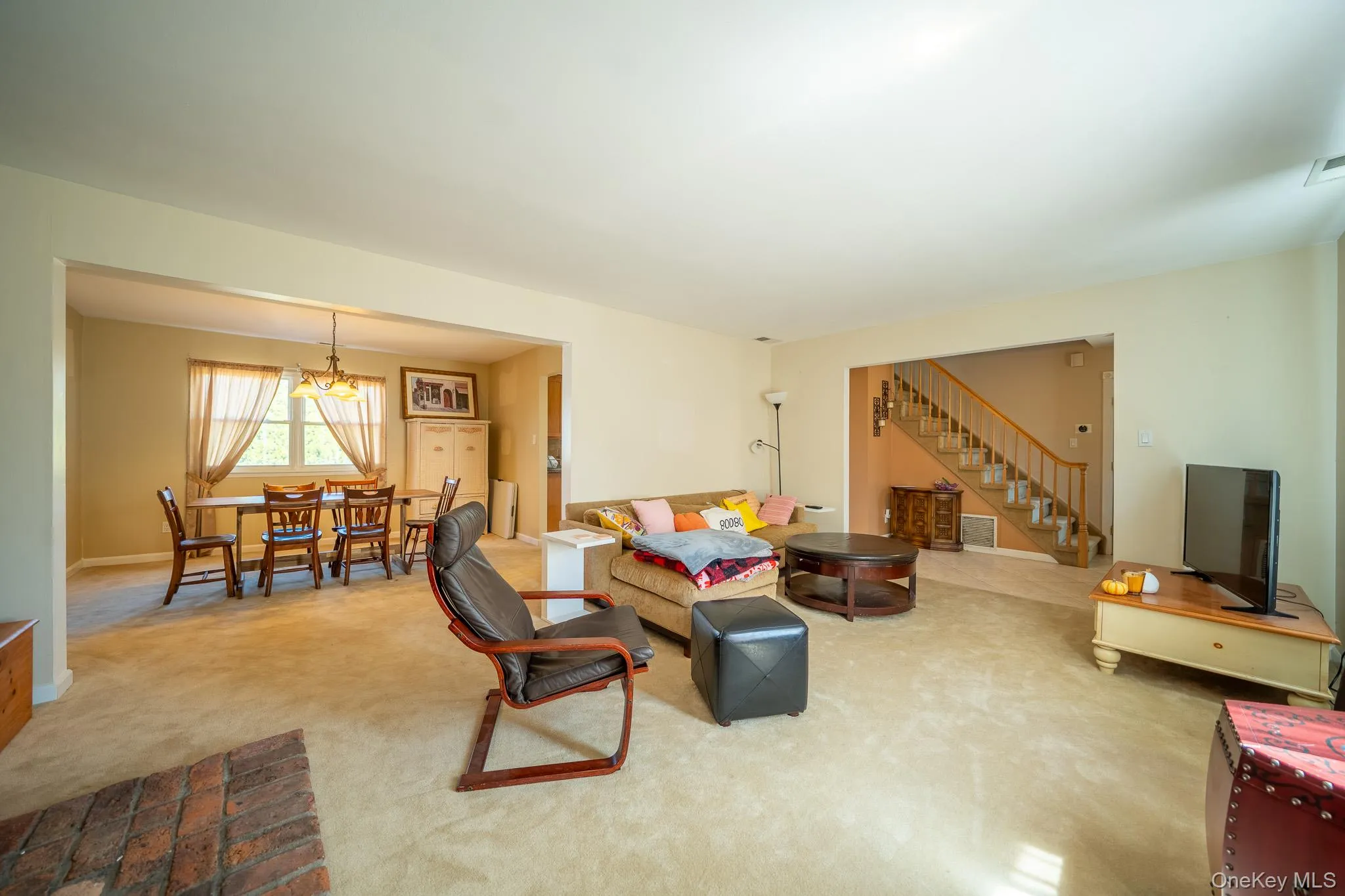 Living room featuring carpet floors, stairs, and visible vents Living room featuring carpet floors, stairs, and visible vents