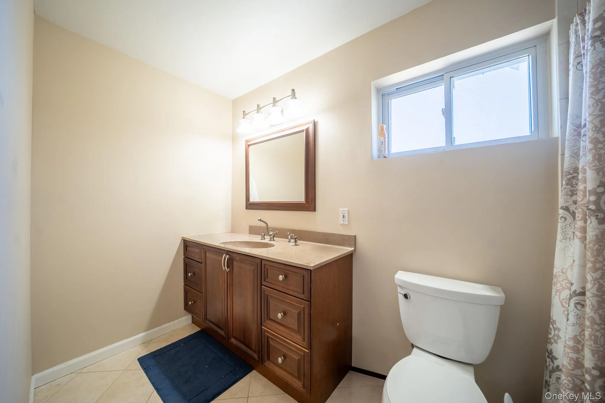 Bathroom featuring baseboards, toilet, vanity, and tile patterned floors Bathroom featuring baseboards, toilet, vanity, and tile patterned floors