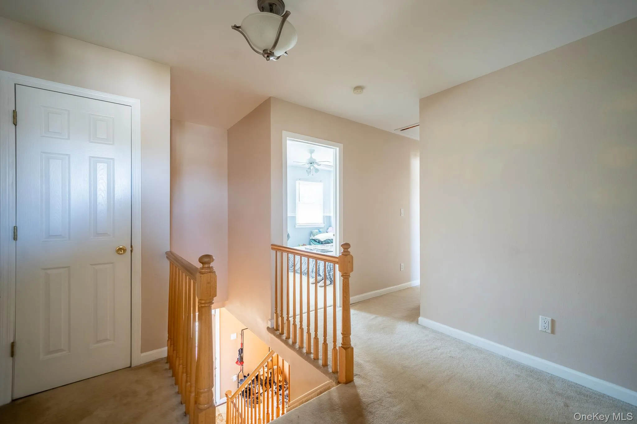 Hallway featuring baseboards, carpet floors, and an upstairs landing Hallway featuring baseboards, carpet floors, and an upstairs landing