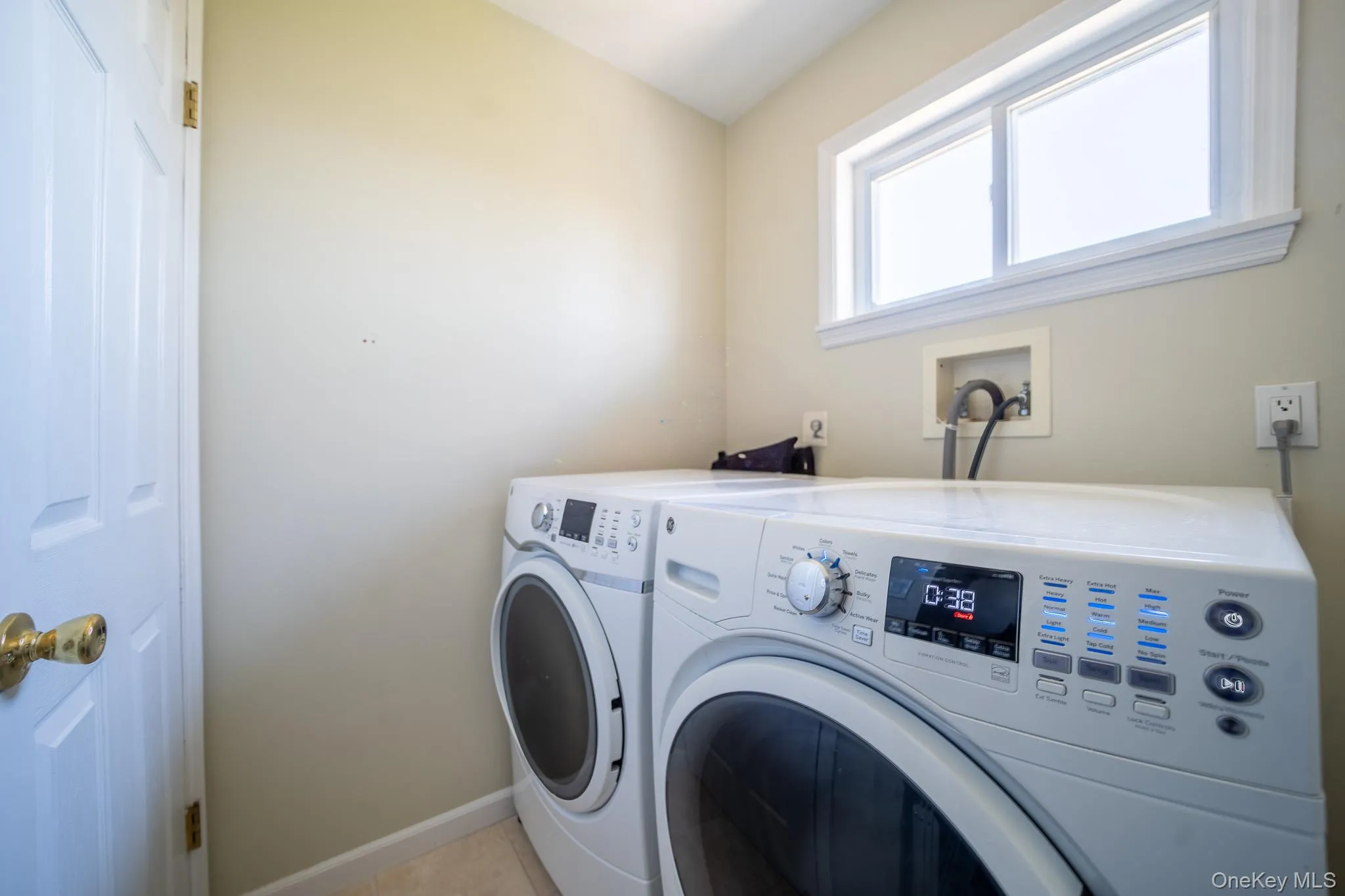 Washroom featuring washing machine and clothes dryer, light tile patterned flooring, laundry area, and baseboards Washroom featuring washing machine and clothes dryer, light tile patterned flooring, laundry area, and baseboards