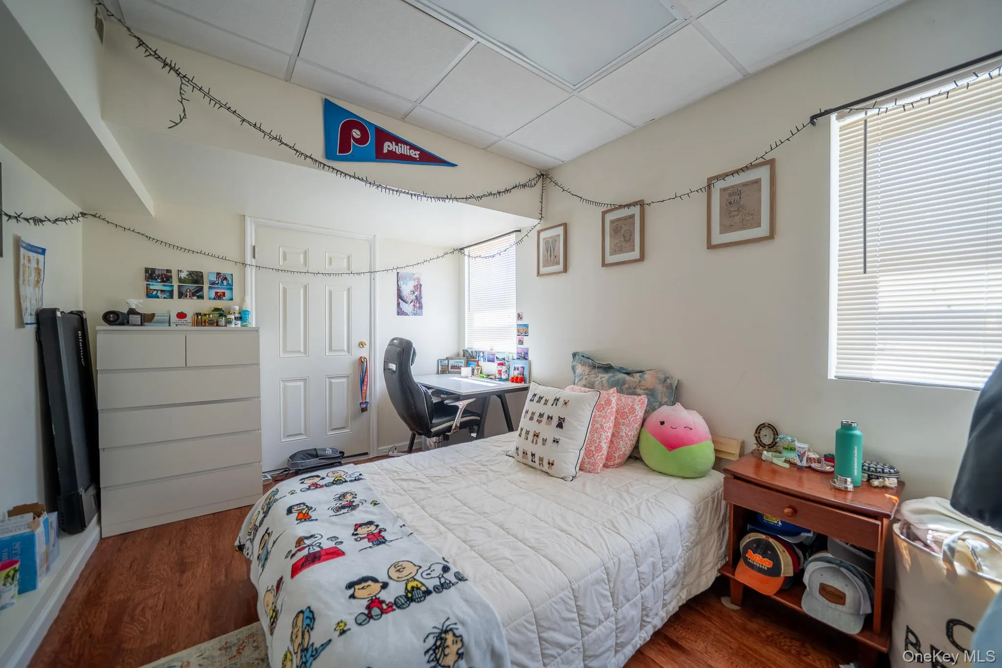 Bedroom with a paneled ceiling, wood finished floors, and multiple windows Bedroom with a paneled ceiling, wood finished floors, and multiple windows