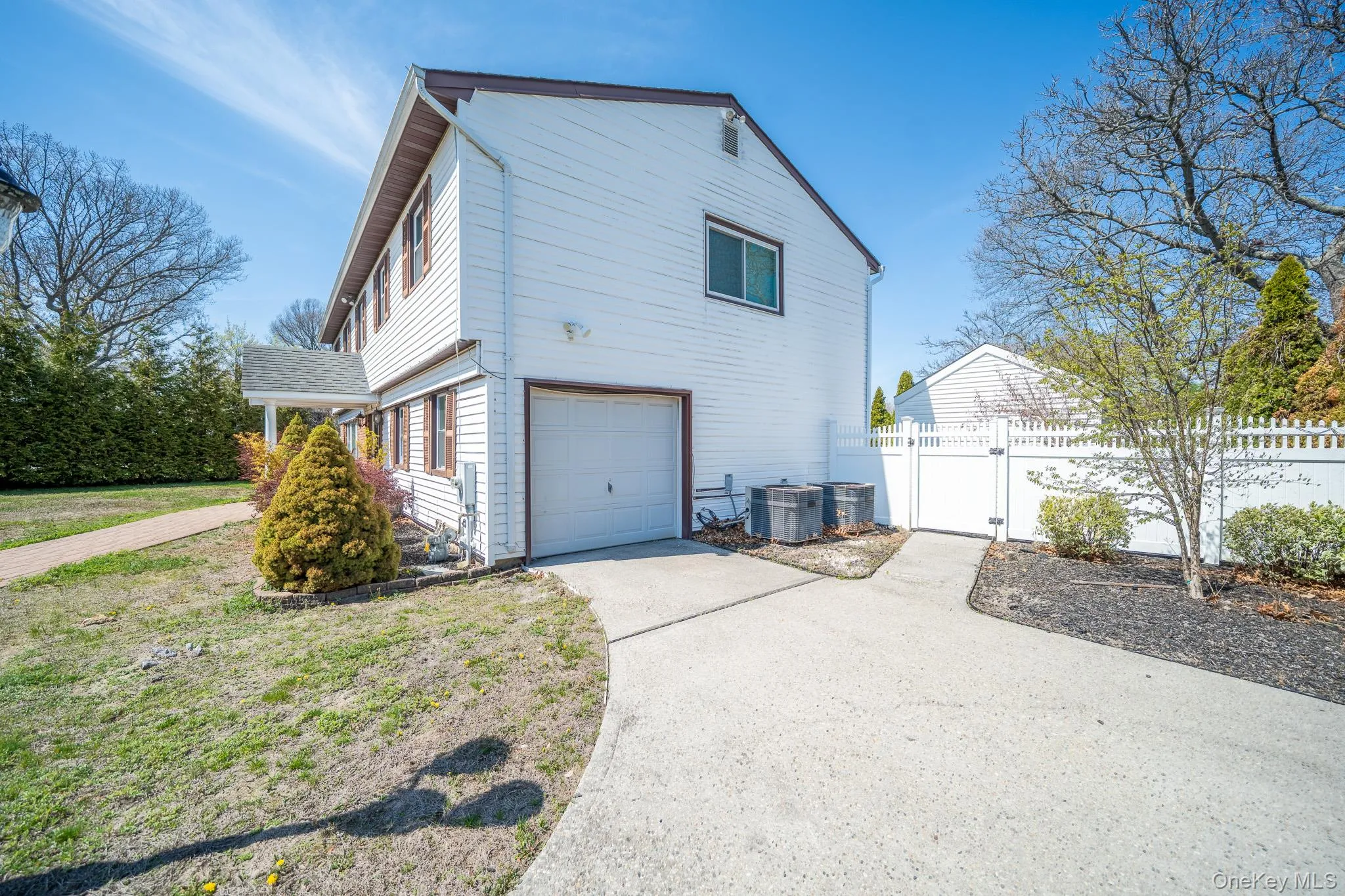 View of property exterior featuring a gate, cooling unit, driveway, fence, and a garage View of property exterior featuring a gate, cooling unit, driveway, fence, and a garage