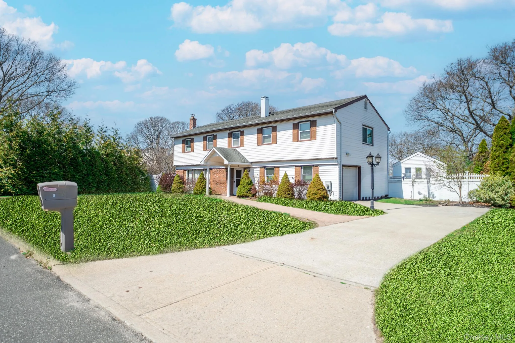 View of front facade featuring a chimney, fence, driveway, brick siding, and a garage View of front facade featuring a chimney, fence, driveway, brick siding, and a garage