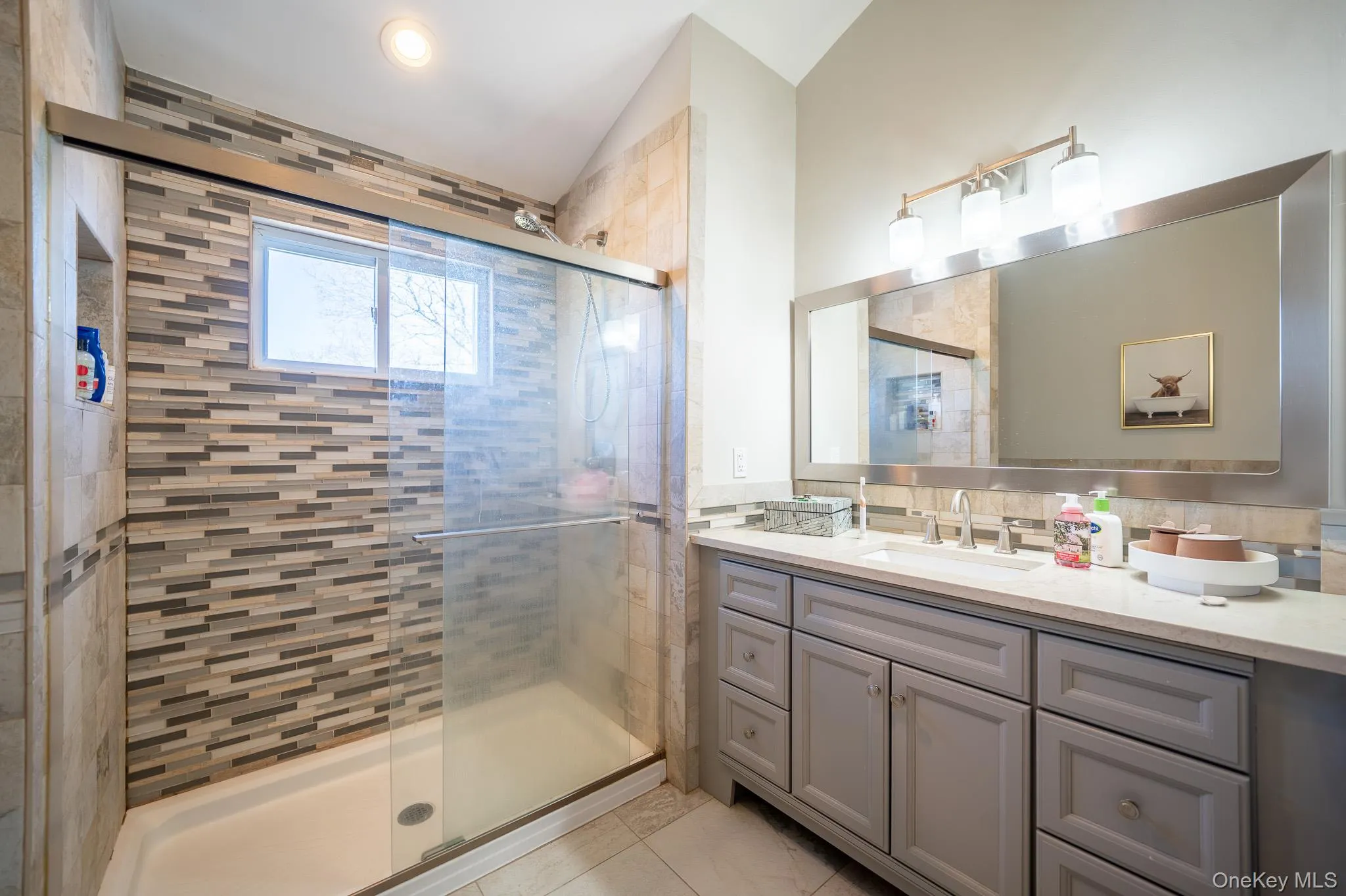 Full bath featuring lofted ceiling, vanity, and a stall shower Full bath featuring lofted ceiling, vanity, and a stall shower