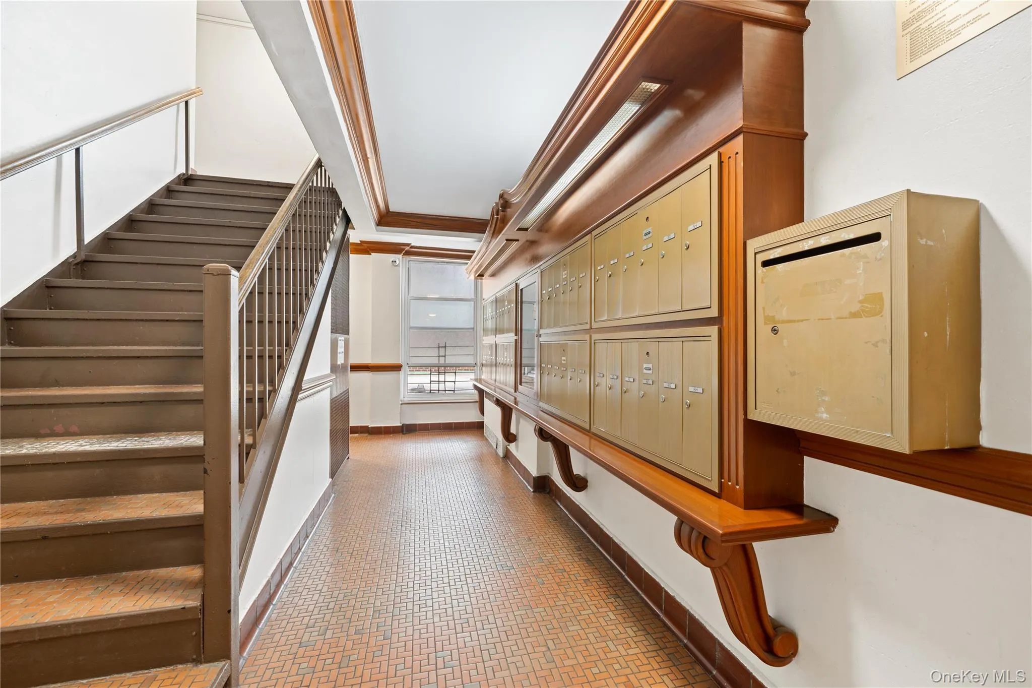 Stairwell featuring wood-finish banister, metal handrail, and patterned tile flooring Stairwell featuring wood-finish banister, metal handrail, and patterned tile flooring