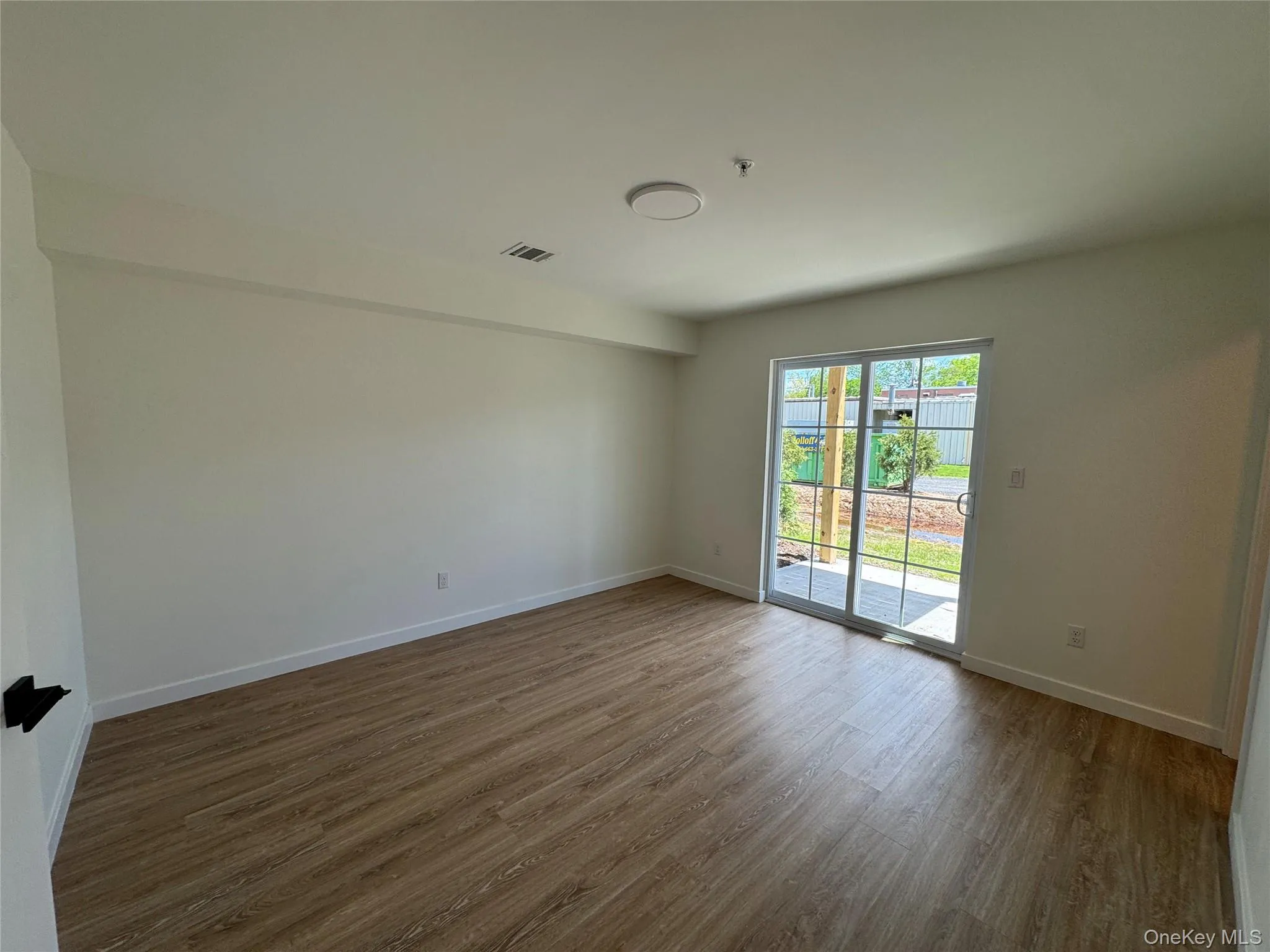 Unfurnished room with dark wood finished floors, baseboards, and fire sprinkler in ceiling Unfurnished room with dark wood finished floors, baseboards, and fire sprinkler in ceiling