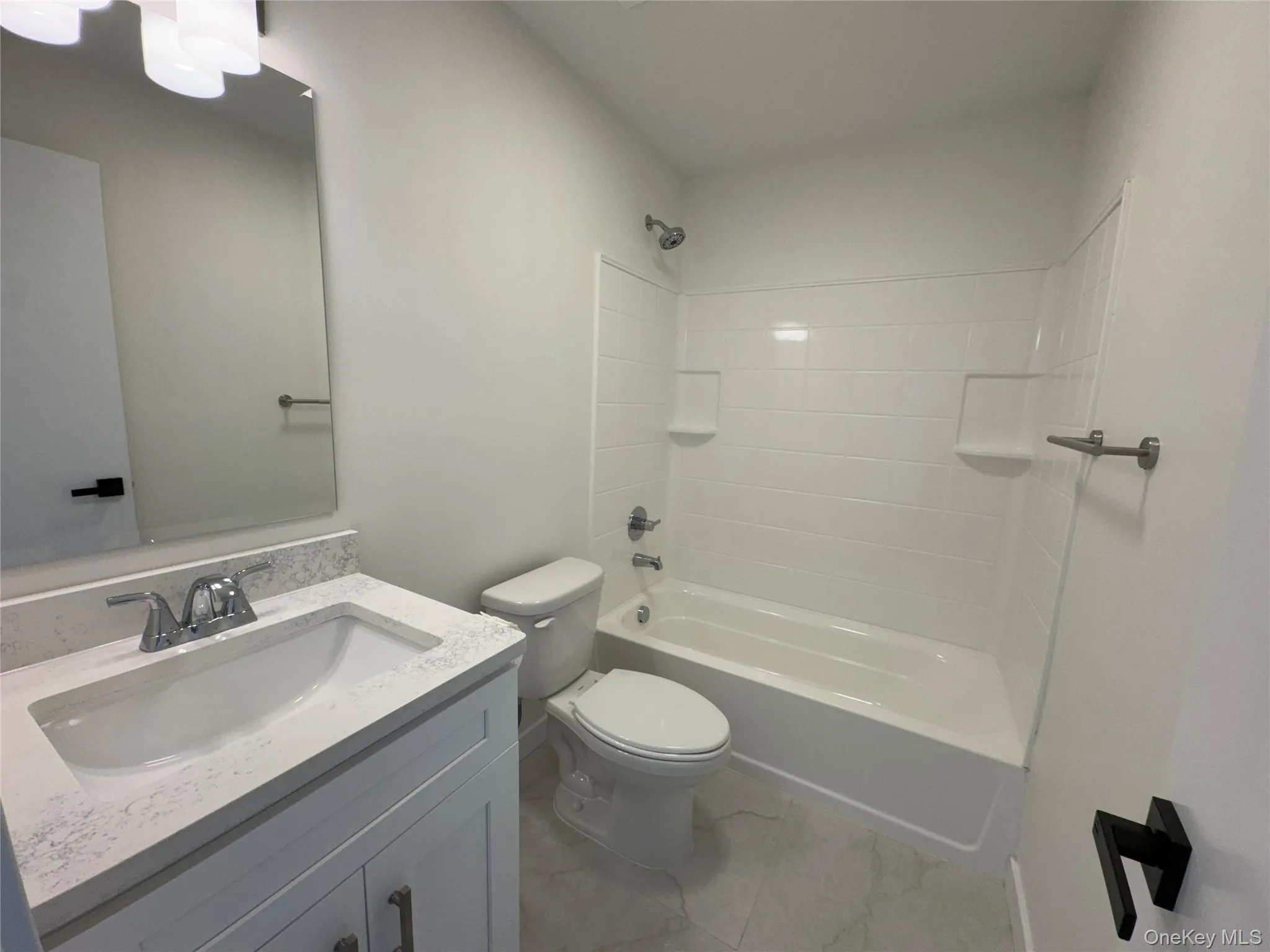 Full bath with toilet, vanity, tub / shower combination, and marble look tiles Full bath with toilet, vanity, tub / shower combination, and marble look tiles