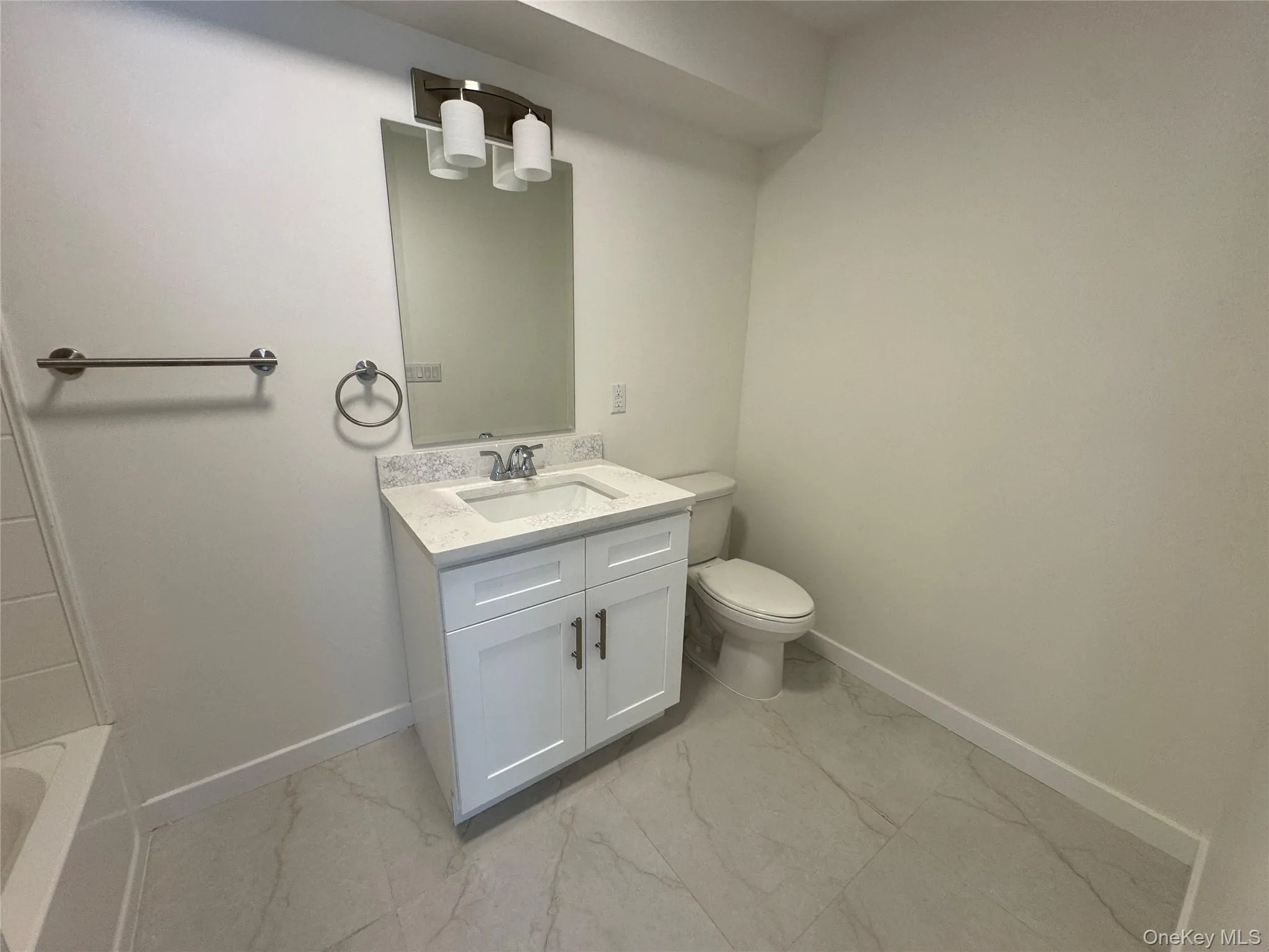 Full bath with marble finish flooring, baseboards, toilet, vanity, and a bathtub Full bath with marble finish flooring, baseboards, toilet, vanity, and a bathtub