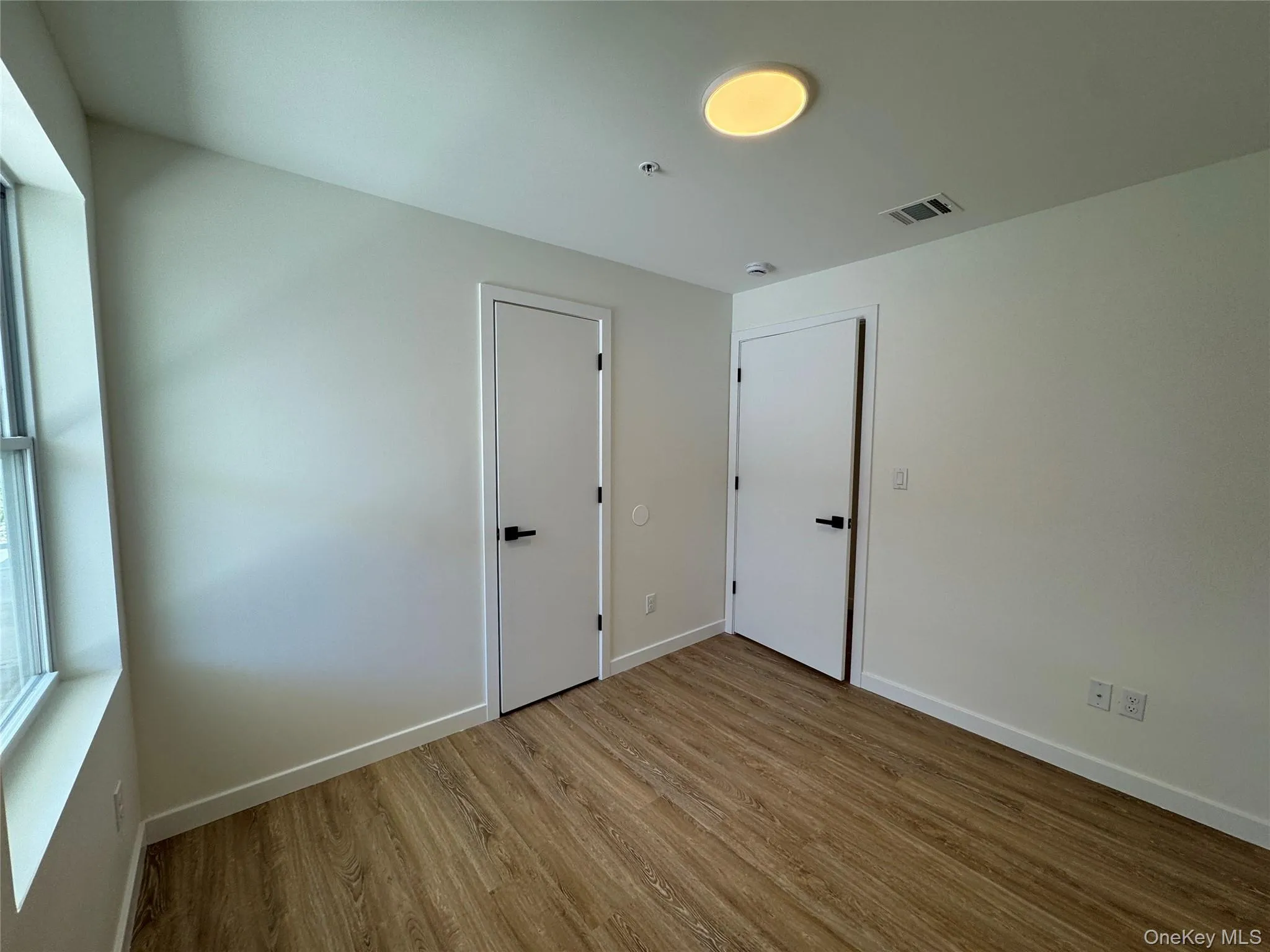 Unfurnished room featuring wood finished floors and baseboards Unfurnished room featuring wood finished floors and baseboards