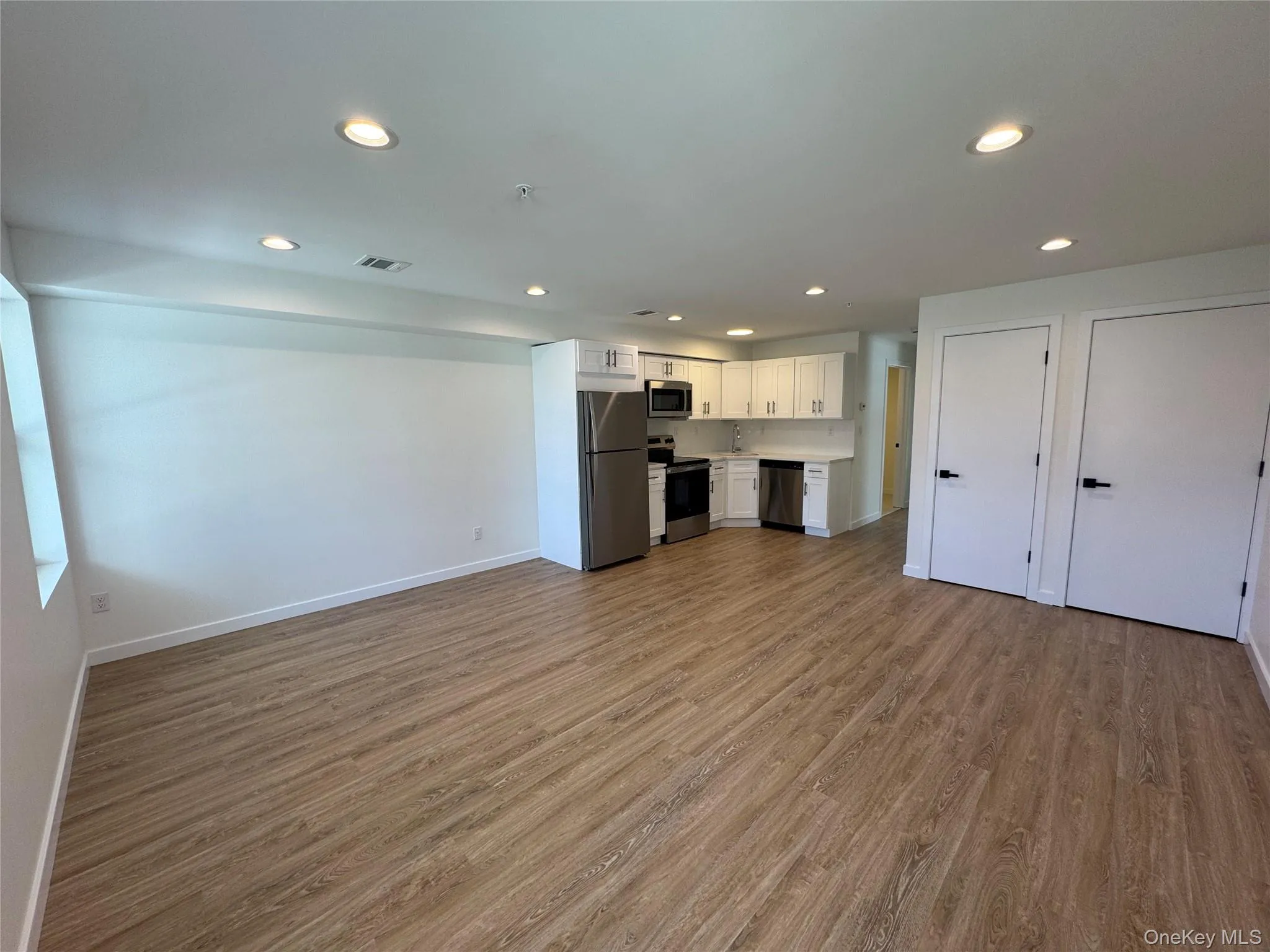 Unfurnished living room featuring wood finished floors, recessed lighting, and baseboards Unfurnished living room featuring wood finished floors, recessed lighting, and baseboards