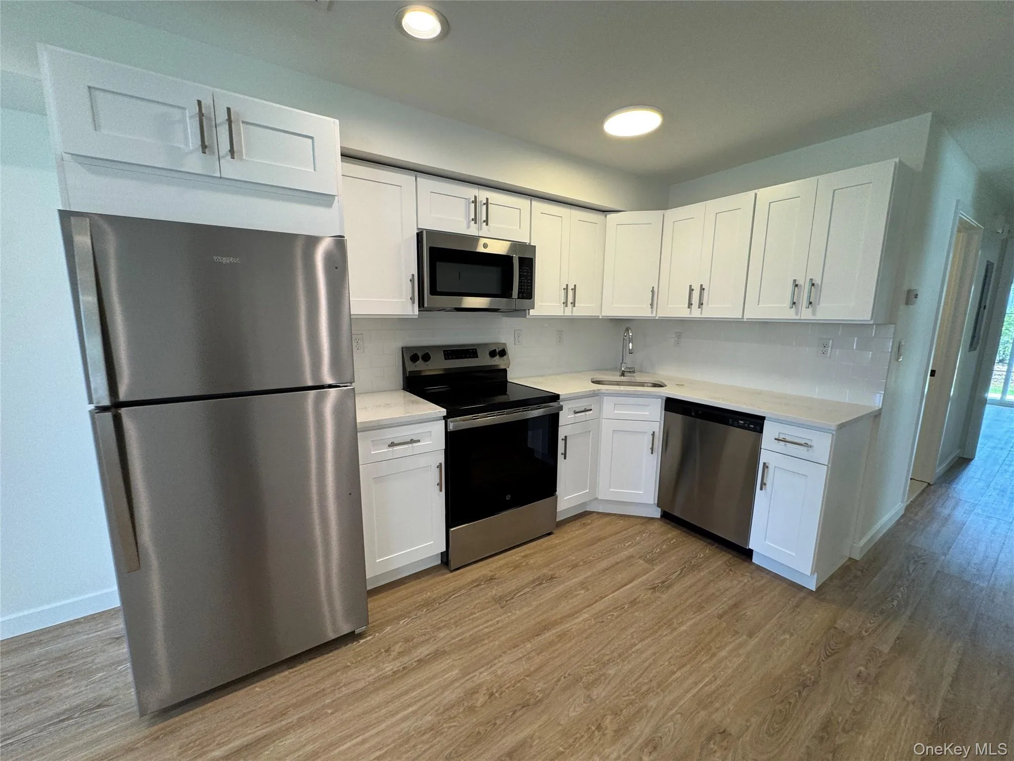 Kitchen with stainless steel appliances, a sink, light wood-type flooring, light countertops, and recessed lighting Kitchen with stainless steel appliances, a sink, light wood-type flooring, light countertops, and recessed lighting