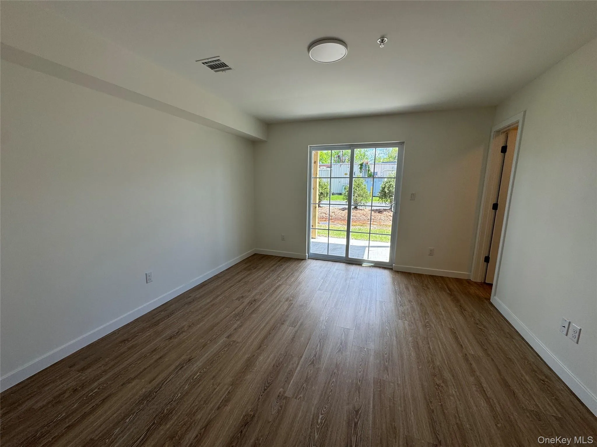 Unfurnished room featuring dark wood finished floors, fire sprinkler in ceiling, and baseboards Unfurnished room featuring dark wood finished floors, fire sprinkler in ceiling, and baseboards