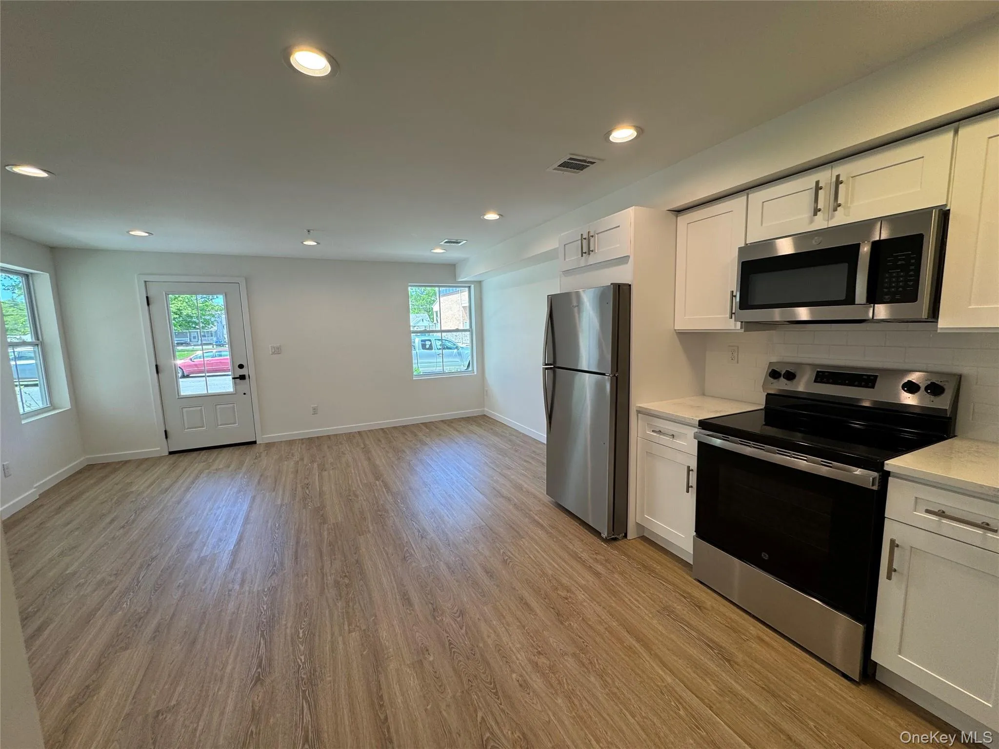 Kitchen featuring stainless steel appliances, white cabinetry, light wood-style flooring, recessed lighting, and baseboards Kitchen featuring stainless steel appliances, white cabinetry, light wood-style flooring, recessed lighting, and baseboards