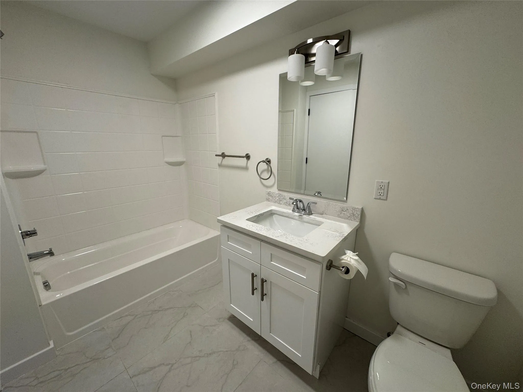 Full bathroom featuring marble finish flooring, toilet, vanity, and shower / tub combination Full bathroom featuring marble finish flooring, toilet, vanity, and shower / tub combination